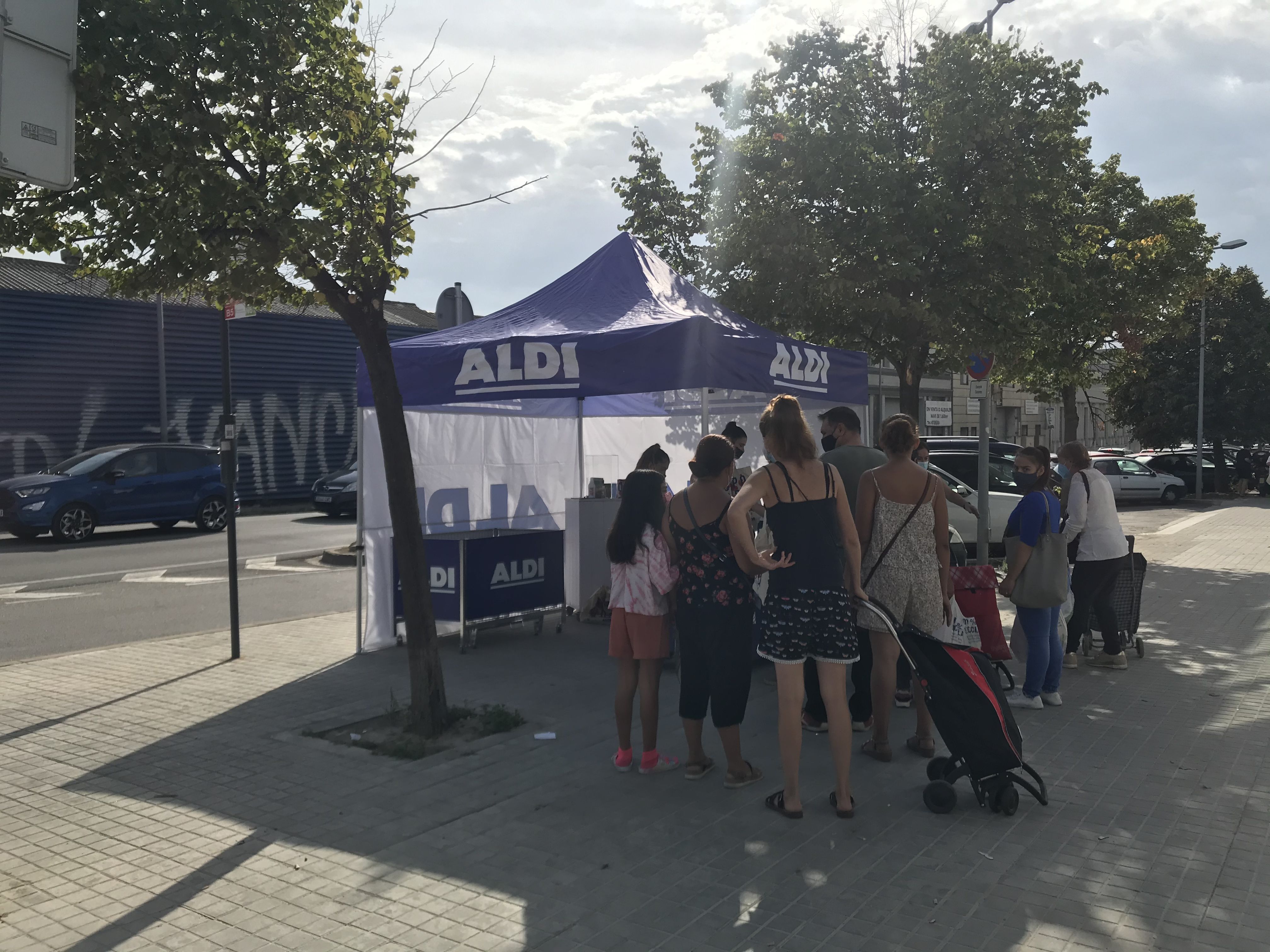 Clients d'Aldi esperen a l'exterior del supermercat per rebre un obsequi el dia de la inauguració.