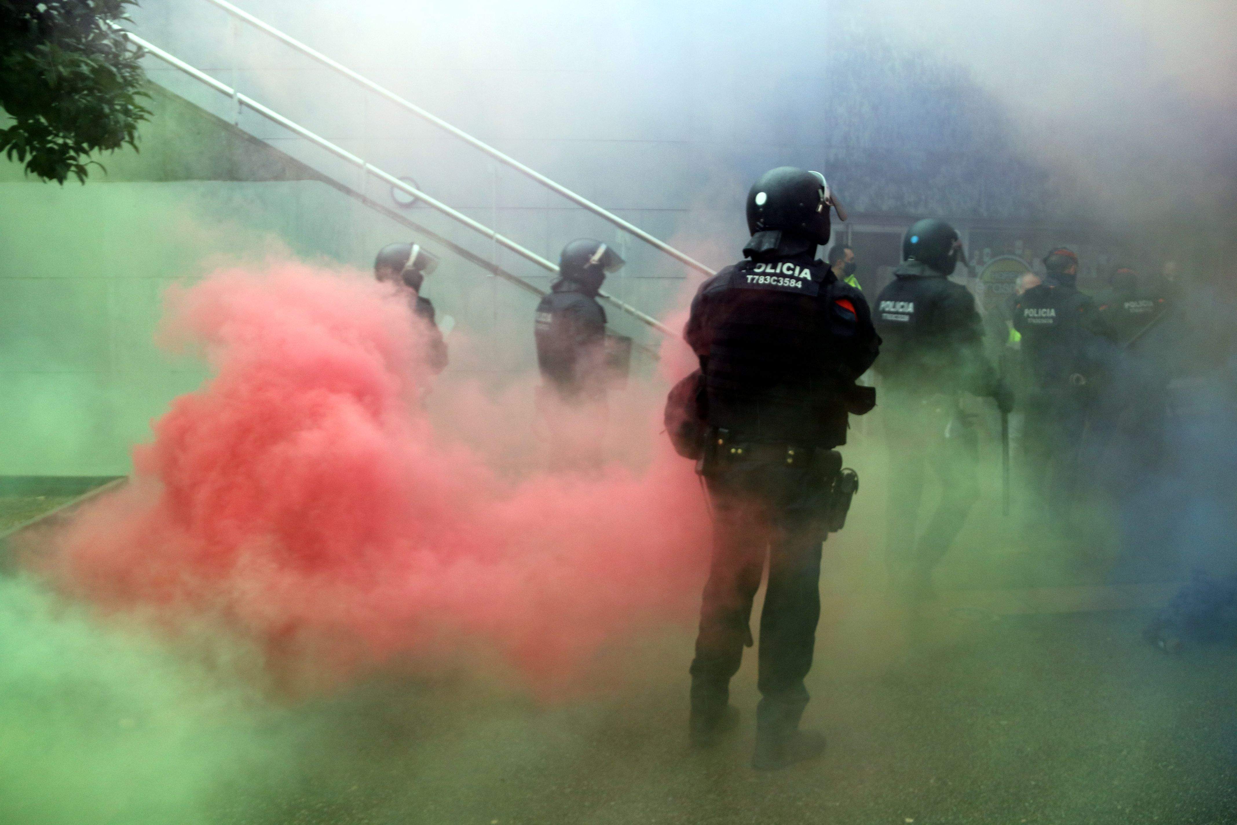 Un agent dels mossos entre pots de fum de colors llançats per manifestants a la UAB. FOTO: Àlex Recolons (ACN)