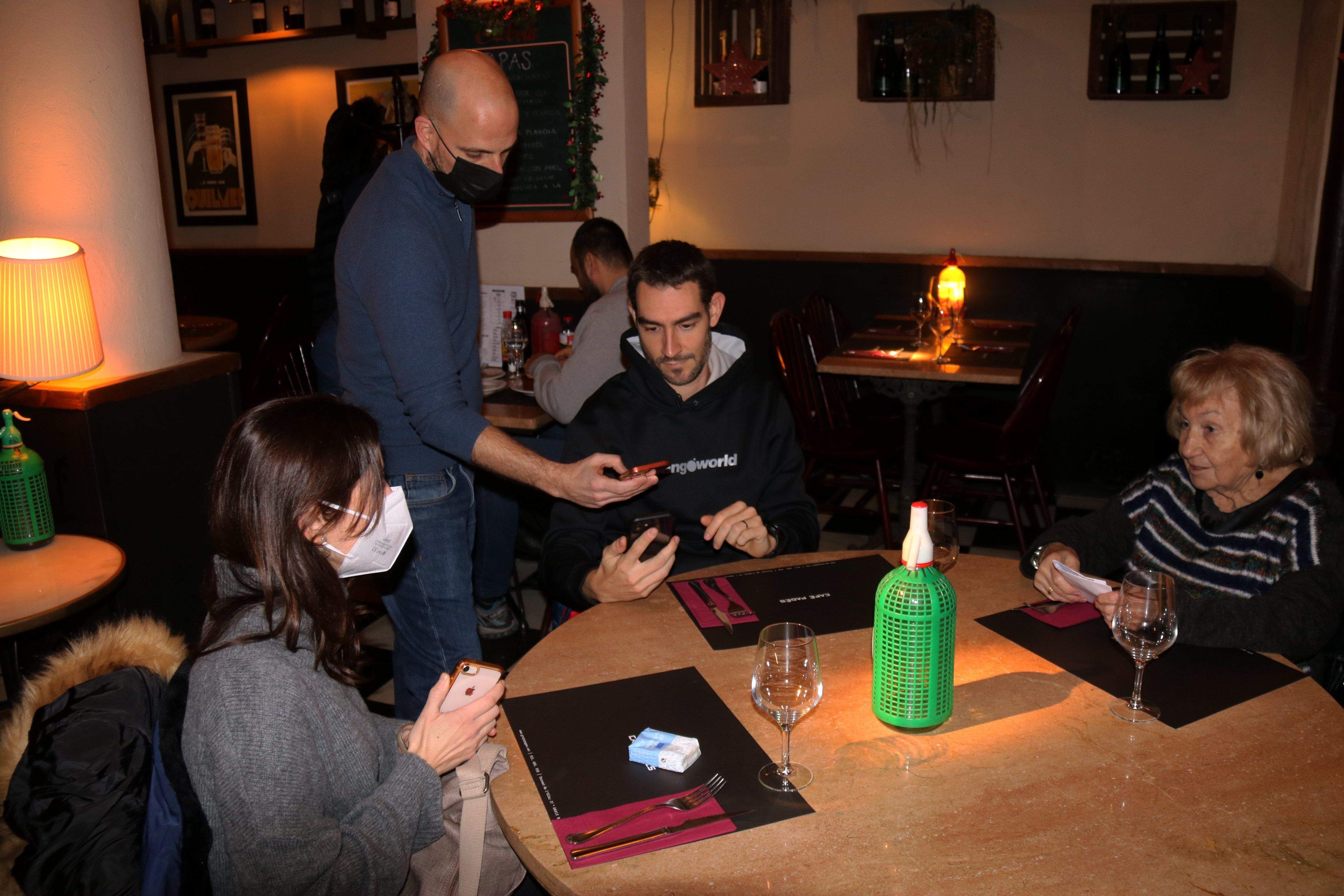 Un cambrer escanejant el codi QR del certificat covid dels seus clients en un restaurant. FOTO: ACN