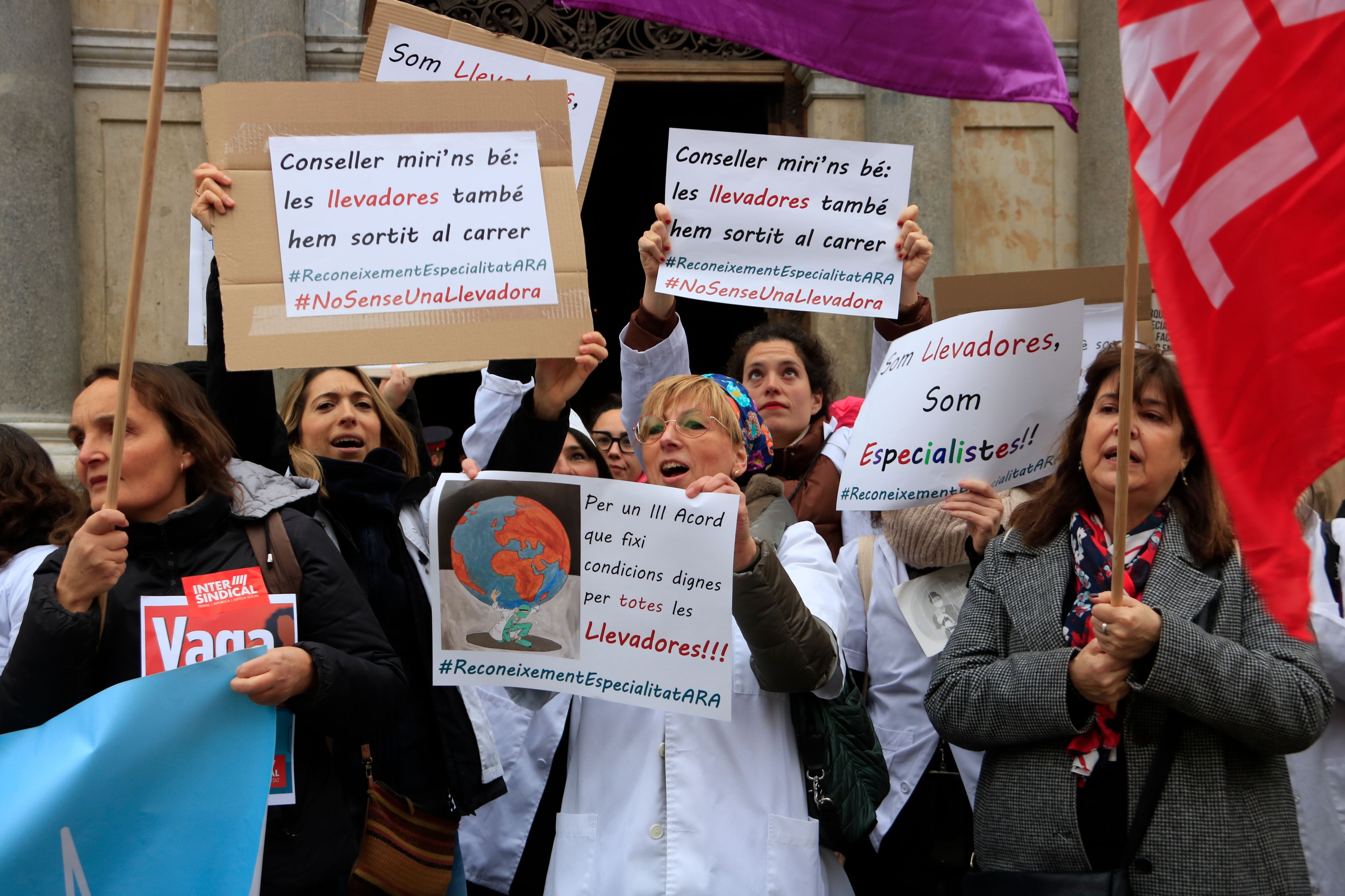 Llevadores en una concentració a la plaça de Sant Jaume de Barcelona porten cartells en què reivindiquen "condicions dignes" en la primera jornada de vaga convocada per la Intersindical al sistema sanitari. FOTO: Laura Fíguls (ACN)