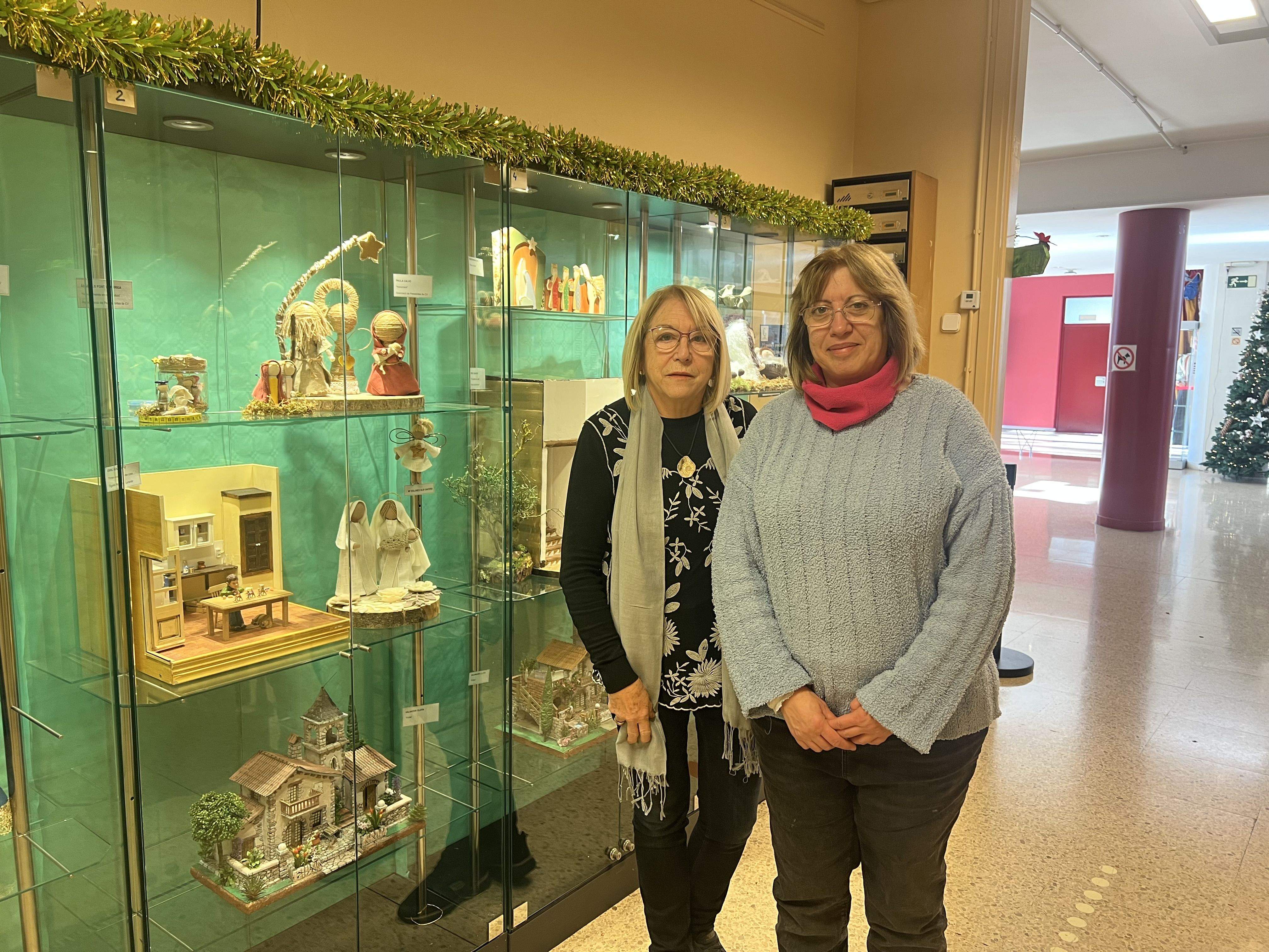 Àngels Font i Maite Montull davant l'exposició de pessebres a l'Ateneu. FOTO: Guillem Barrera