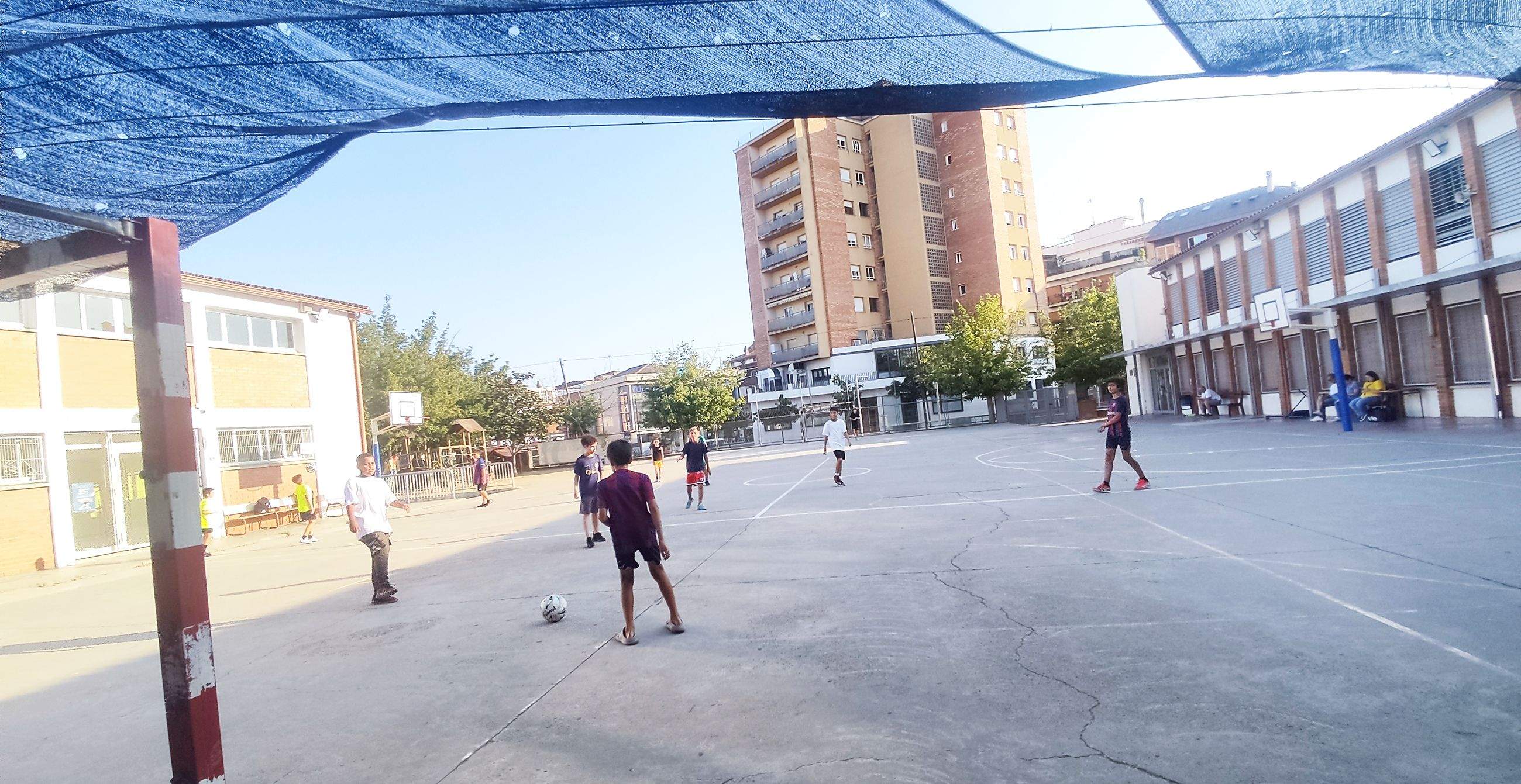 Un grup de joves i infants juguen a futbol a l'escola de Sant Martí, durant els patis oberts. FOTO: TOT