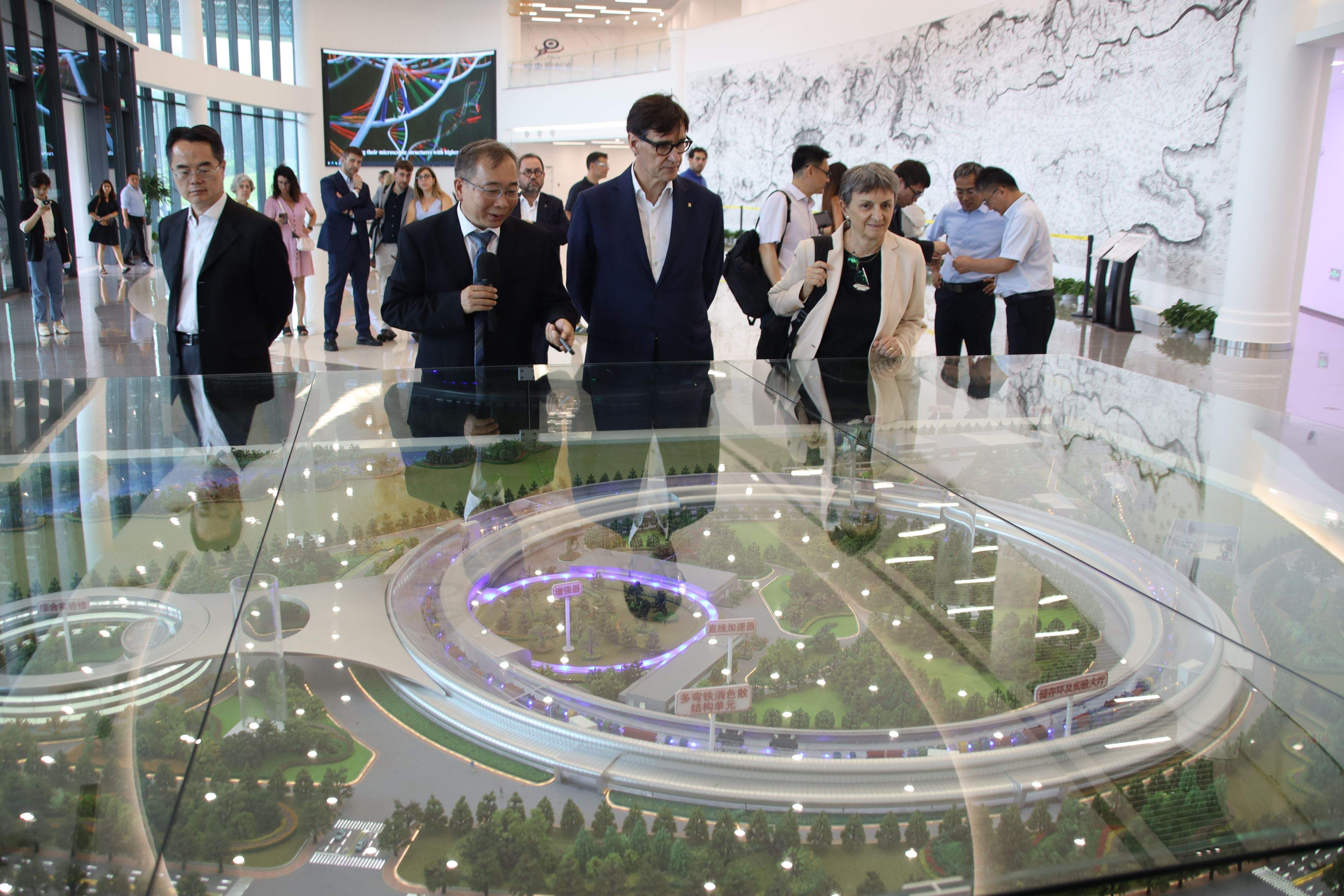 El president de la Generalitat, Salvador Illa, i la directora del Sincrotró ALBA, Caterina Biscari, observant una maqueta del sincrotró de Pequín, a la Xina.  FOTO: Mariona Puig / Albert Segura (ACN)