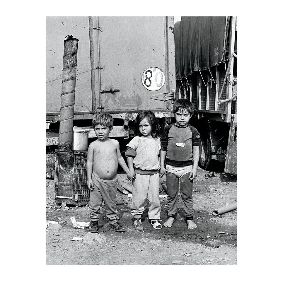 Infància descalça, Tres infants davant un camió, amb la roba bruta i els peus nus. Una escena que retrata la duresa quotidiana d’una infància marcada per la pobresa. Any: 1982 – Fotografia de Vicenç Semper