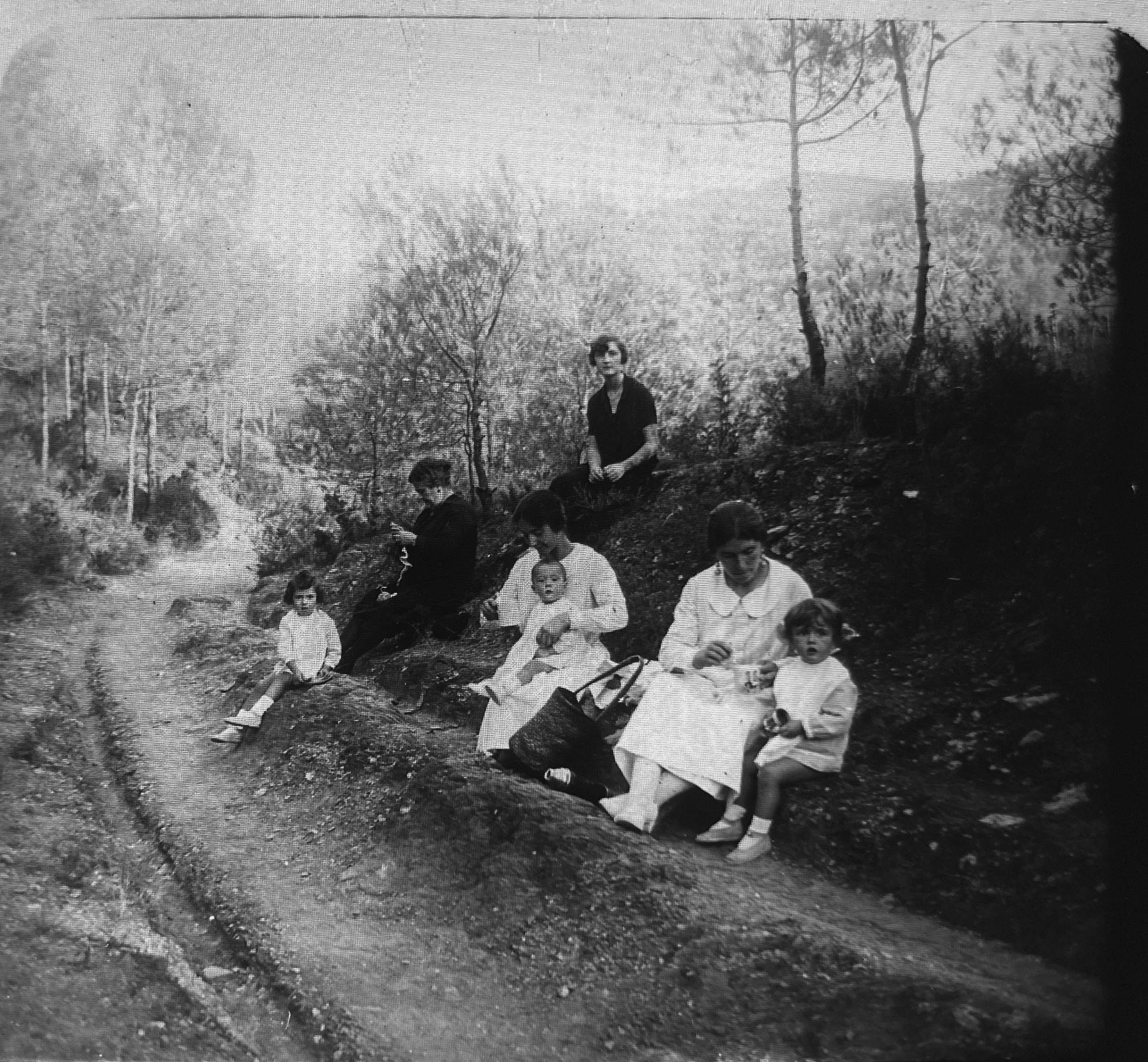 Excursió. Grup de dones i infants reposen al marge d’un camí de bosc. La imatge transmet el ritme pausat de les vacances de fa més de cent anys. FOTO: Família Recolons / @GREC