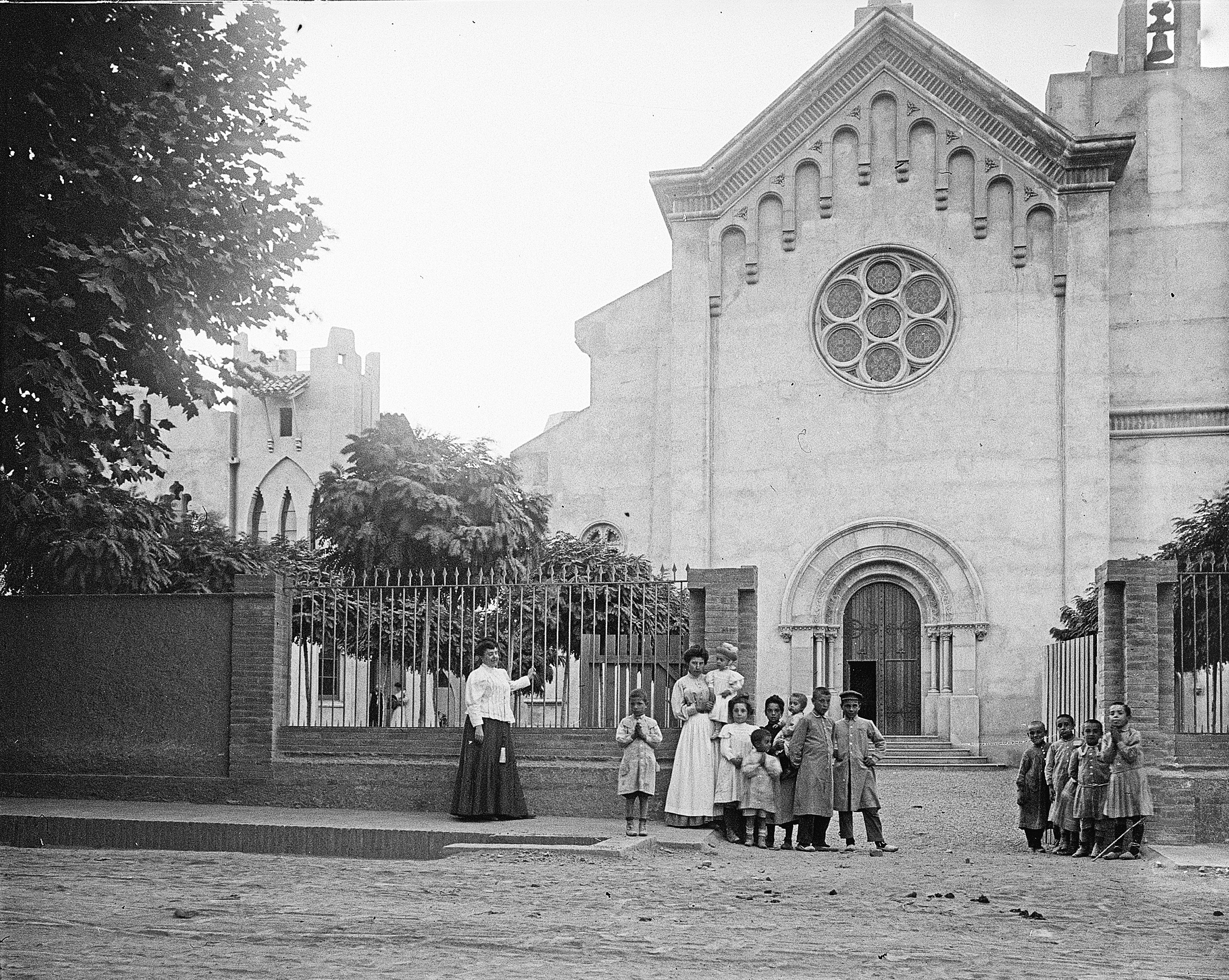 L’església de Sant Martí sense campanar. Fotografia de principis del segle XX que mostra la façana de l’església de Sant Martí abans de la construcció del campanar. Davant, un grup de nens i mestresses, potser sortint d’escola o de missa, ens regala un moment de vida quotidiana a la Cerdanyola de fa més d’un segle.. FOTO: Jaume Oliveres i Brossa / AFCEC – Fons Jaume Oliveres / @Editorial Efadós