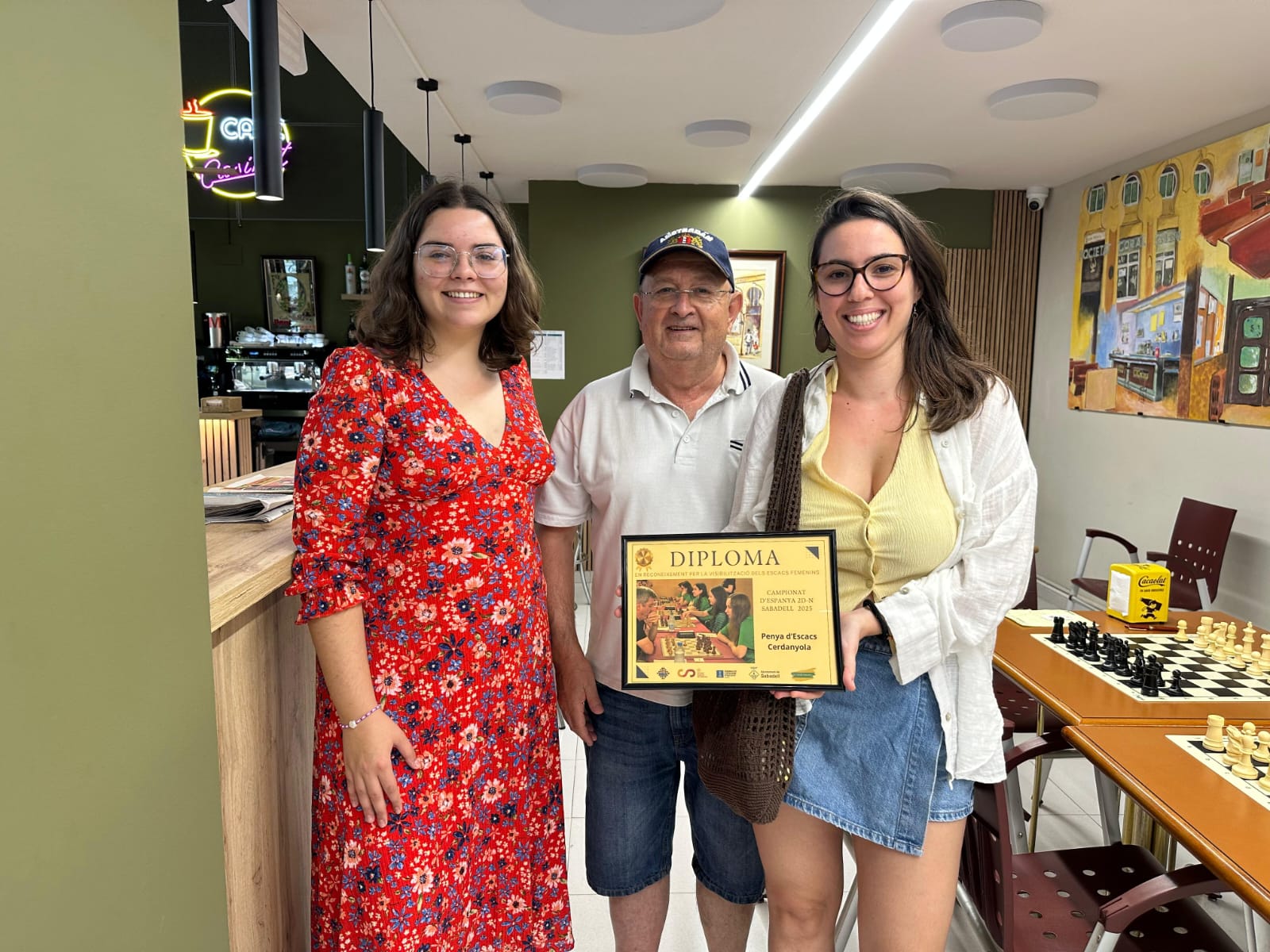 Jaume Grau, president del club de Cerdanyola, i Cora Castellet (dreta), una de les jugadores, rebent el reconeixement de mans de Marina Ponsa, de la Comissió d'igualtat Federació Catalana d'Escacs. Foto: Penya Escacs Cerdanyola
