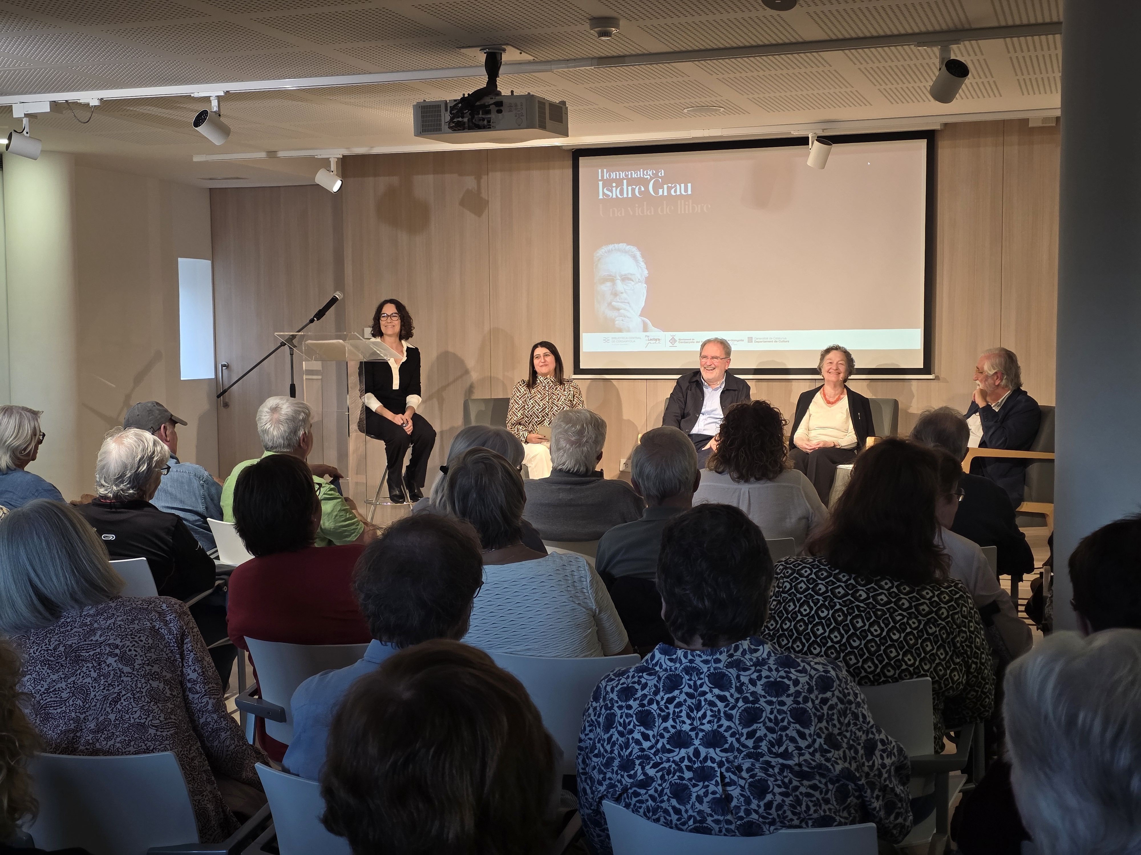 La gent escoltant a l'escriptor cerdanyolenc Isidre Grau en el seu homenatge a la Biblioteca Central. Foto: Marc Mata