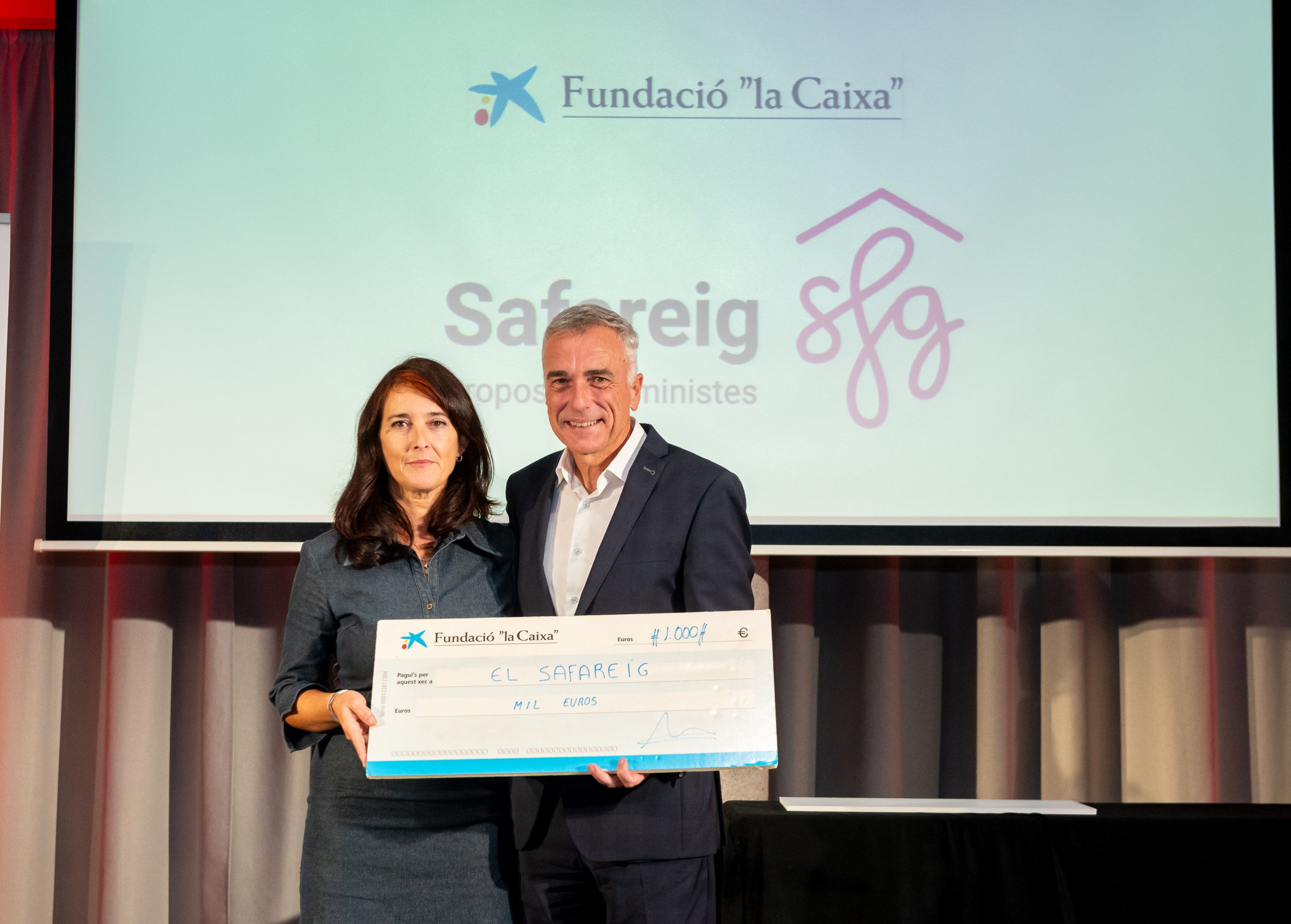 Lídia Vaquero, de l’entitat El Safareig, recull el xec solidari lliurat per Xavier García Hornos, de CaixaBank. FOTO: Xavi Olivé