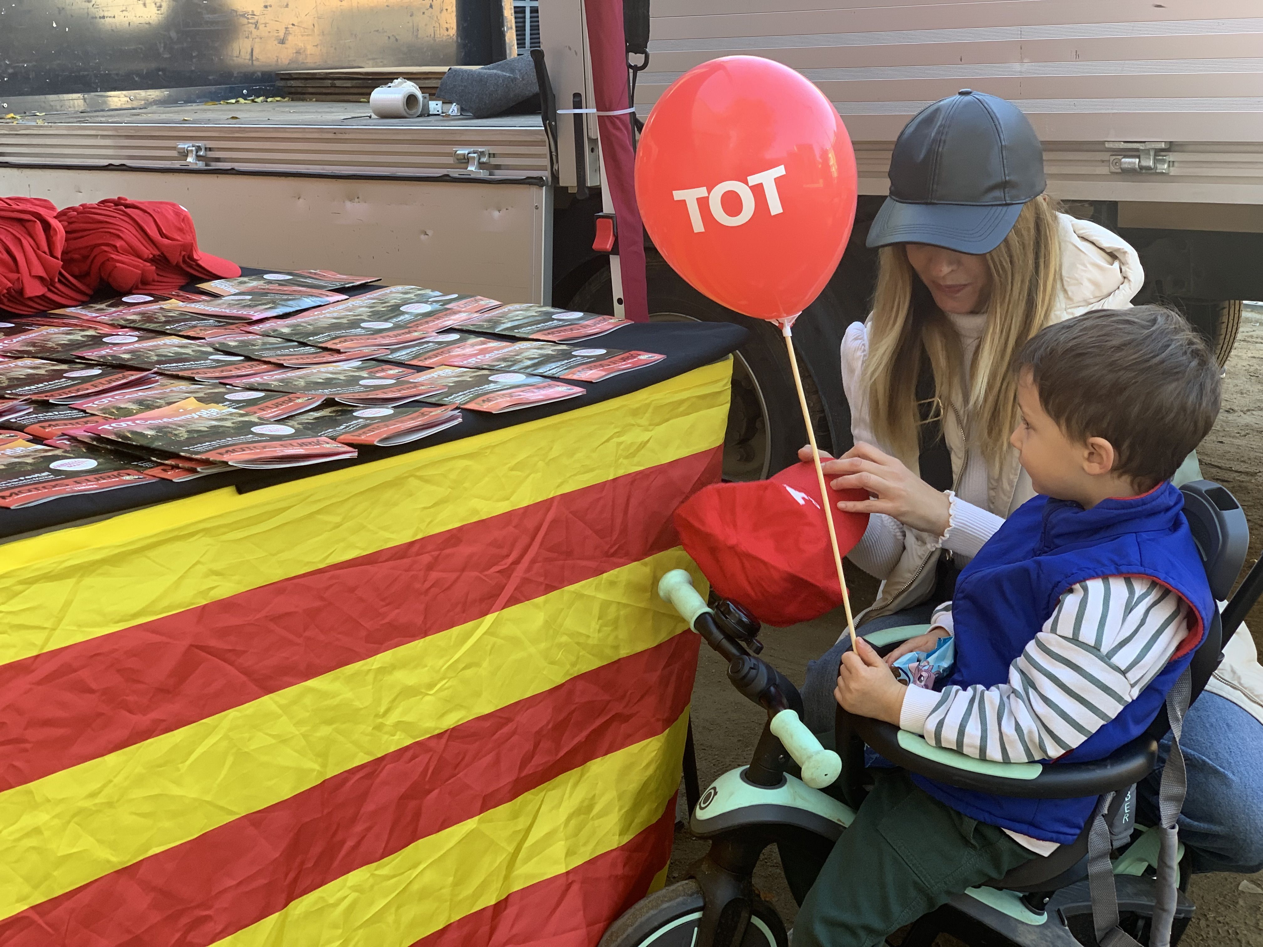 Veïns i veïnes s’acosten a la parada del TOT Cerdanyola durant la Festa de Tardor per endur-se revistes, globus i gorres.