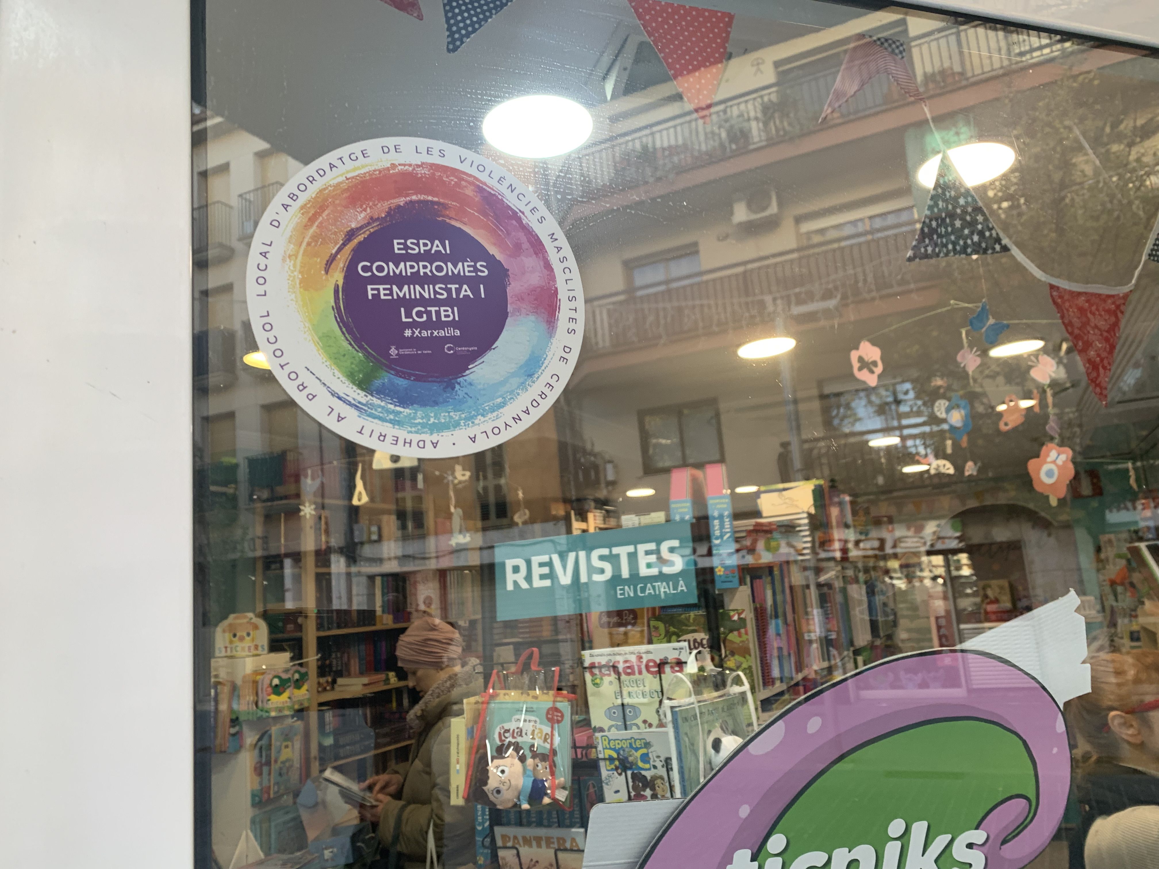 Adhesiu de la Xarxa Lila a l’aparador de Lilliput, que identifica la llibreria com a Espai Compromès Feminista i LGTBI. FOTO: Judit Josa