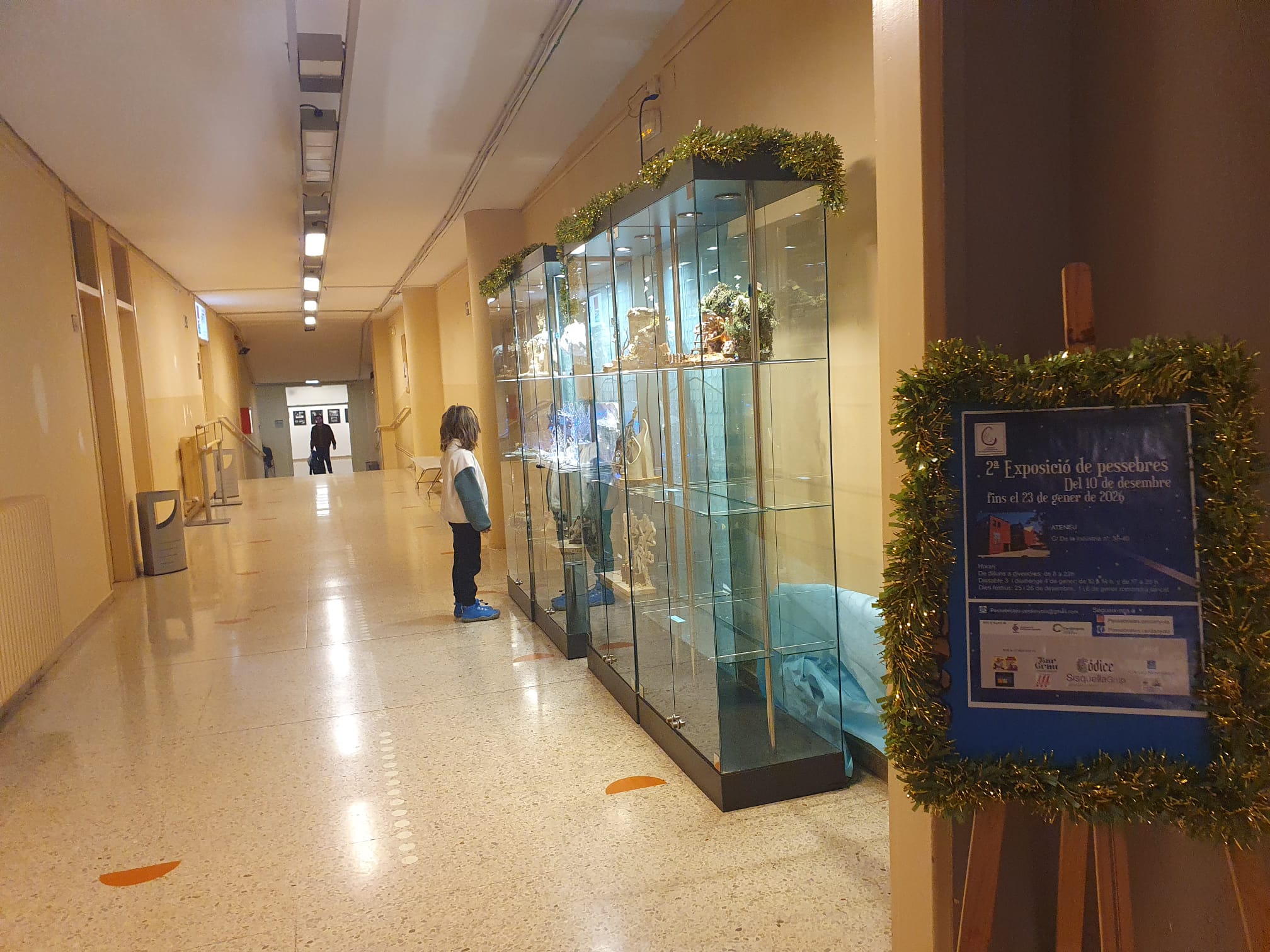 Una nena contempla els naixements exposats en tres vitrines del passadís de l'Ateneu. FOTO: Judit Josa