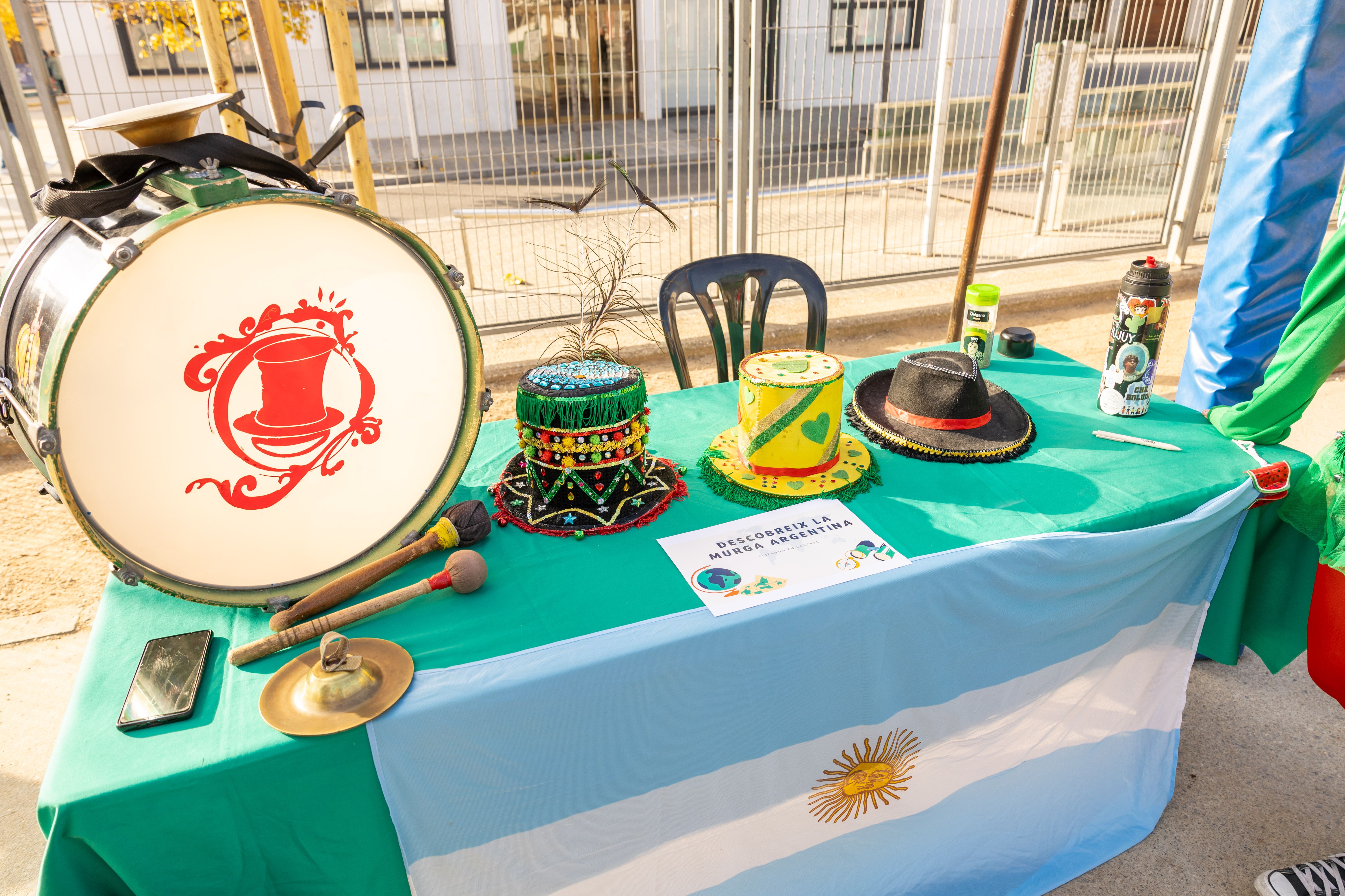 Taula amb elements de la murga argentina i bandera. La murga argentina va posar ritme i identitat cultural a la jornada de la Tardor Solidària. FOTO: Arnau Padilla