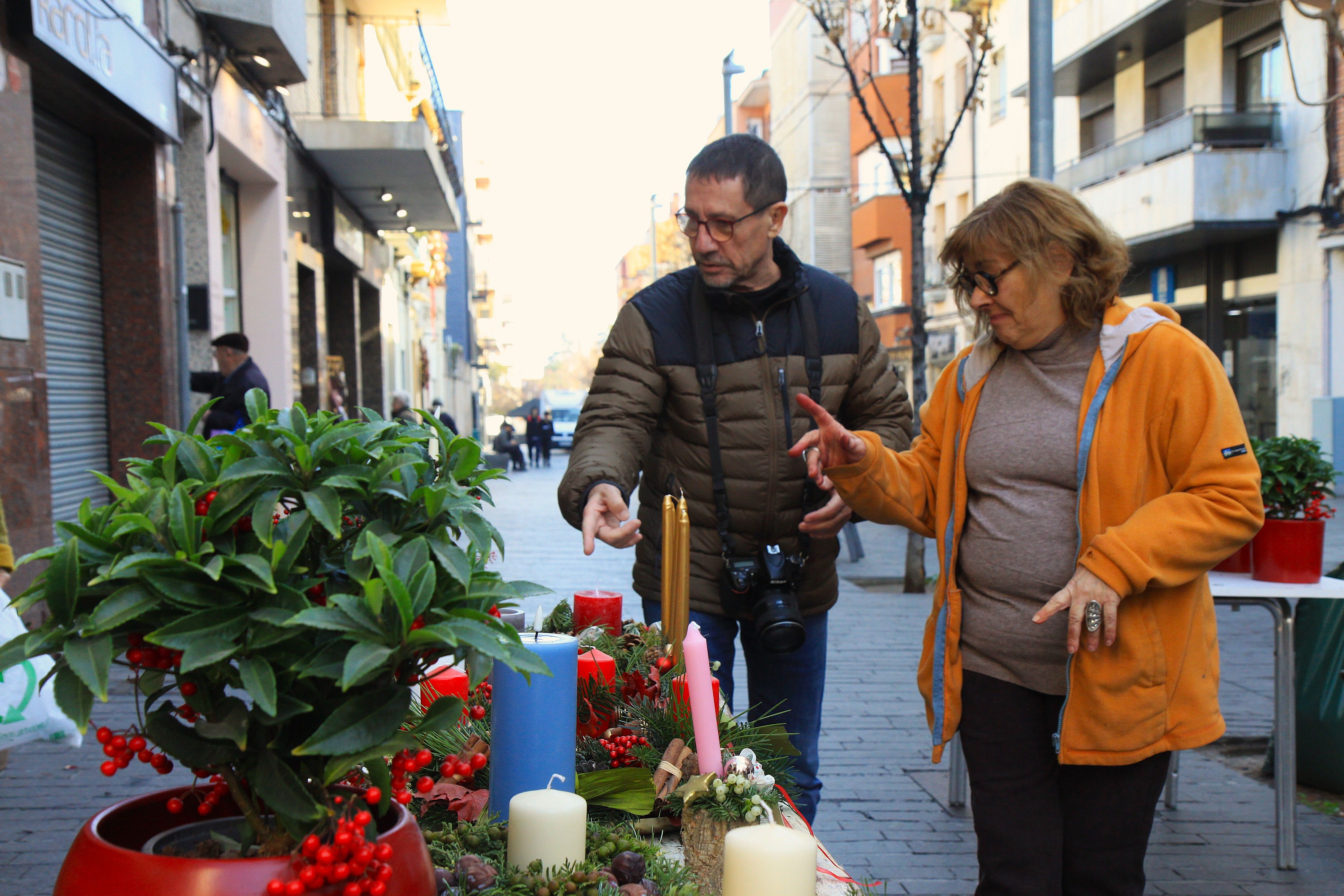 La Maria Casamitjana li ensenya els centres de taula a un client. Foto: Laia Jubany