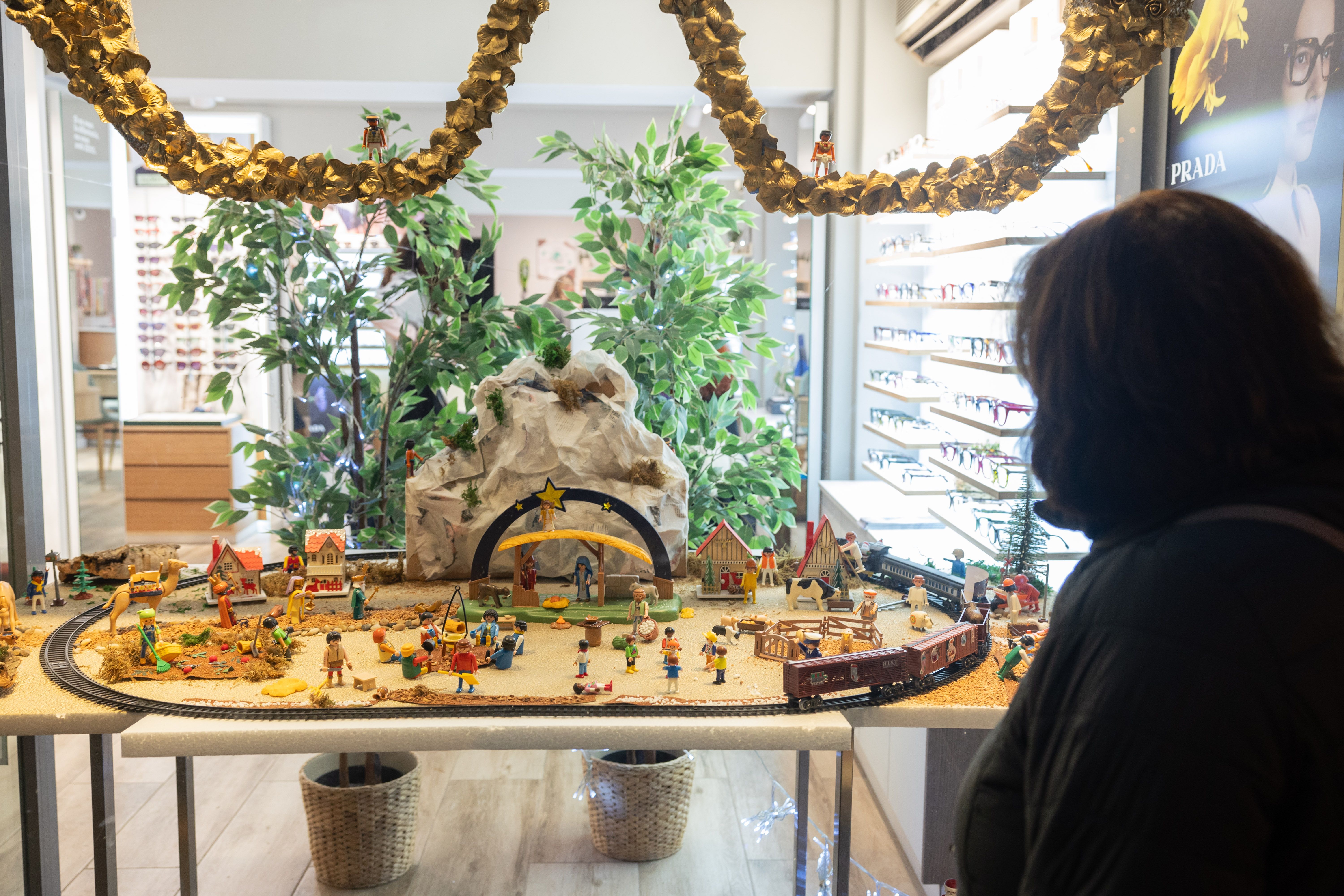 Una dona contempla el pessebre d'opticalia Montflorit, amb una decoració manual en forma d'ulleres. FOTO: Arnau Padilla