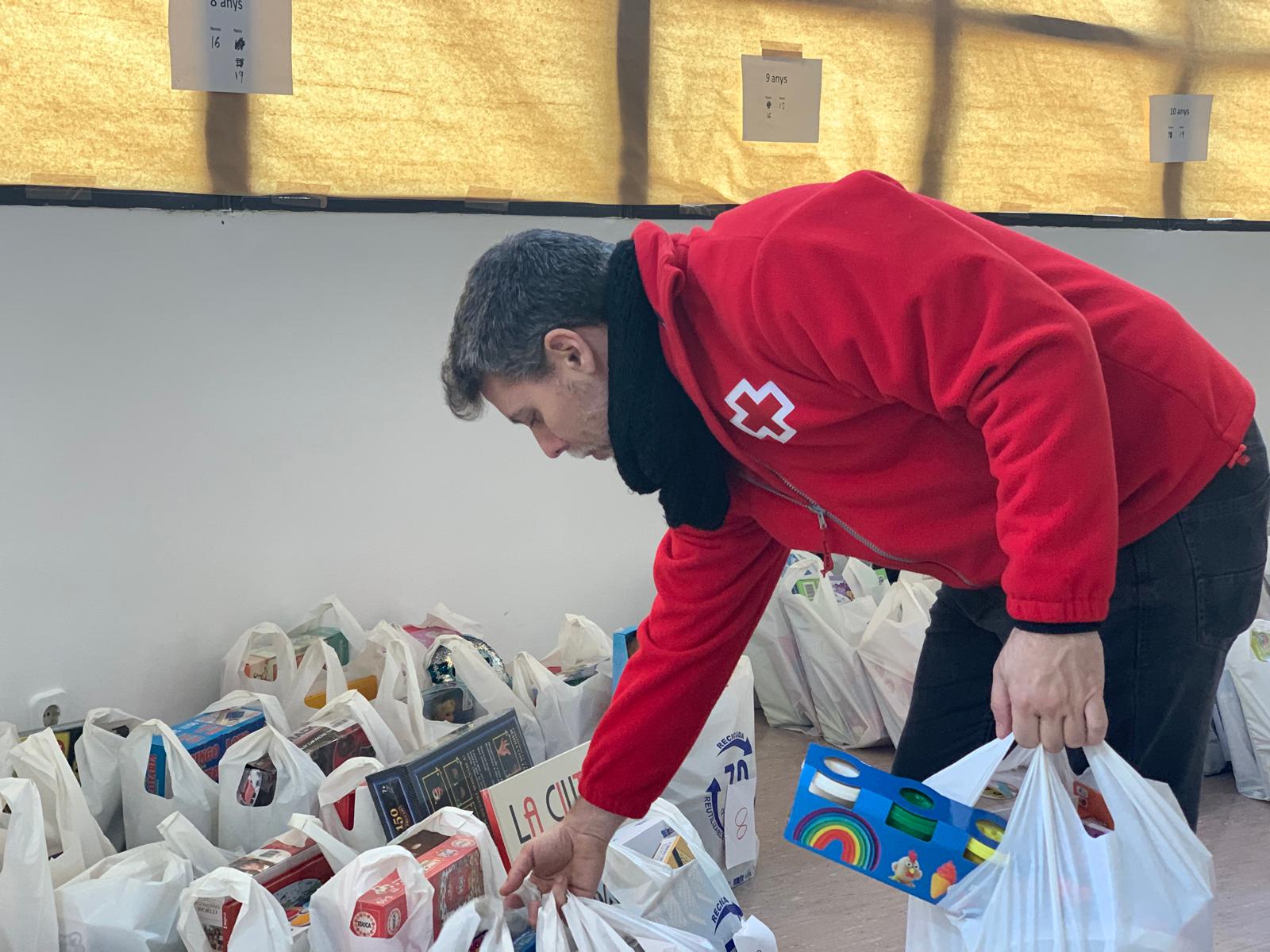 Un voluntari de la Creu Roja prepara aquest divendres els lots de joguines, segons edat dels infants. FOTO: Judit Josa