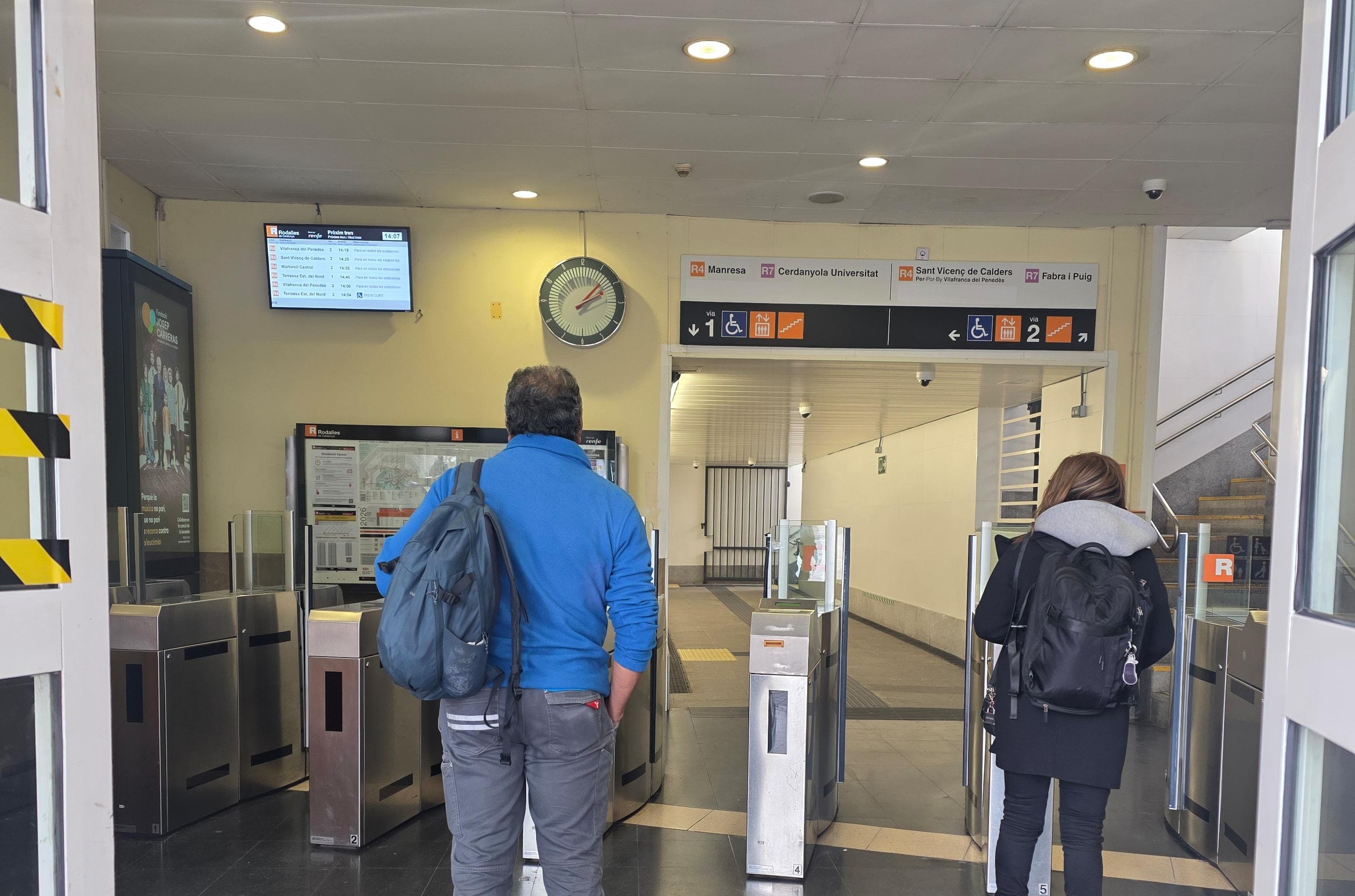 Usuaris mirant la pantalla de l'estació de tren de Cerdanyola. Foto: Marc Mata