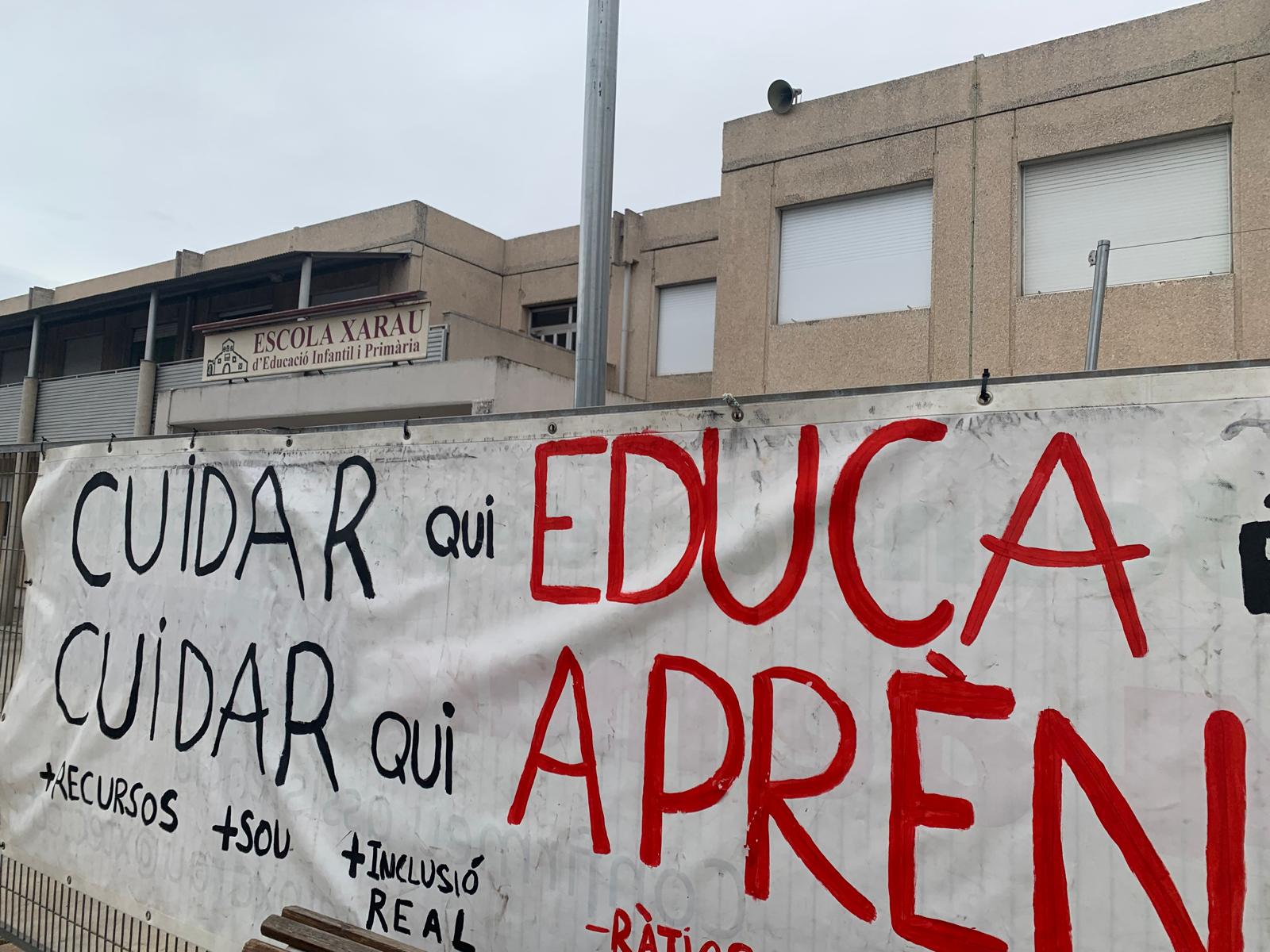 Pancarta a la tanca de l'escola Xarau, ahir, amb les aules pràcticament buides. FOTO: Judit Josa