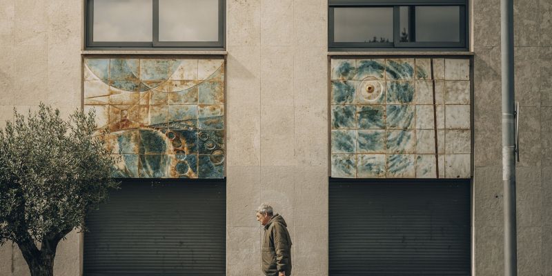 Un vianant passant per davant el murla ceràmic d'Arimany a la façana de l'Ajuntament. Foto: Arnau Padilla
