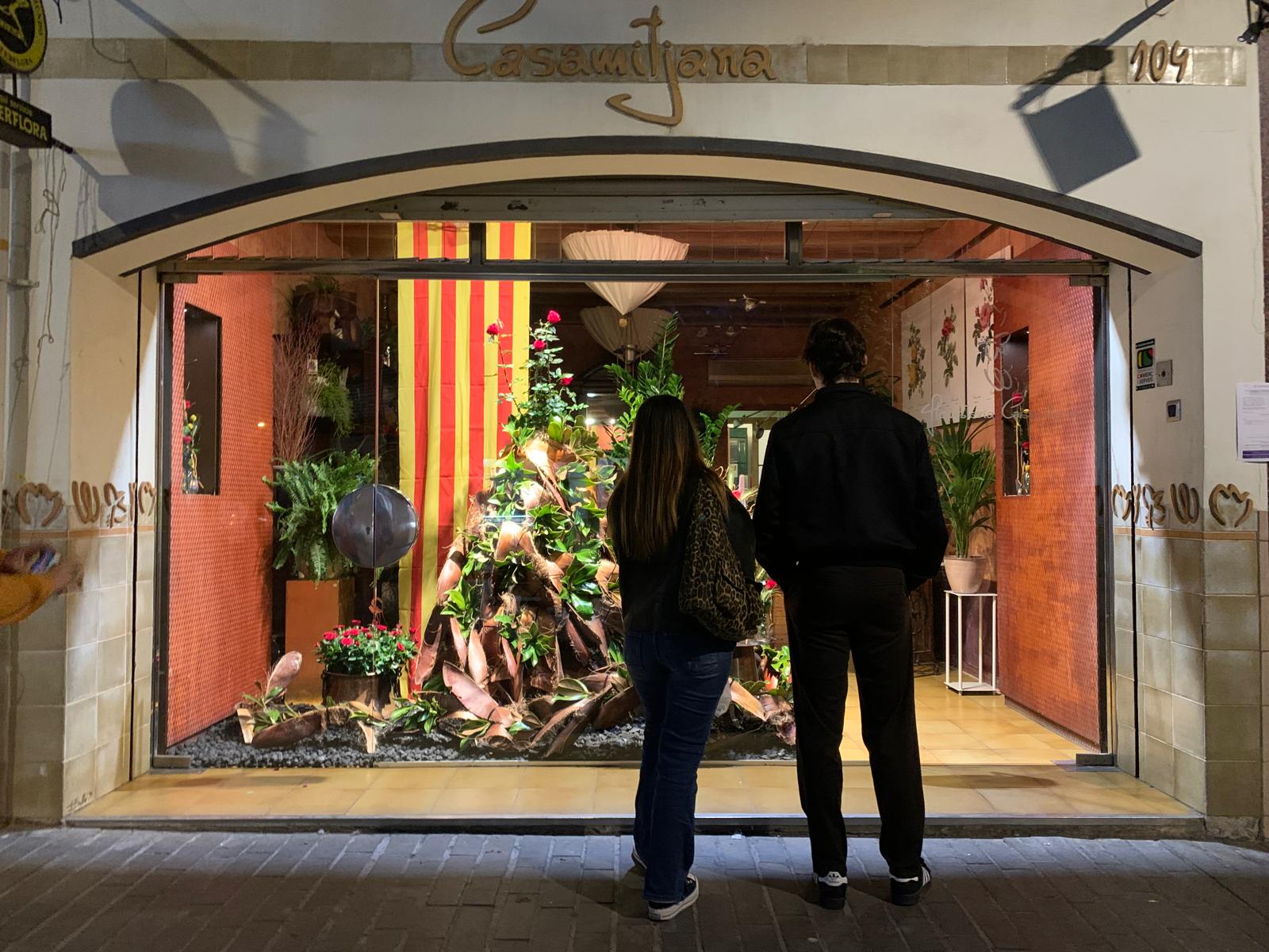 Uns joves contemplen l’escultura floral de l’aparador. Foto: Judit Josa