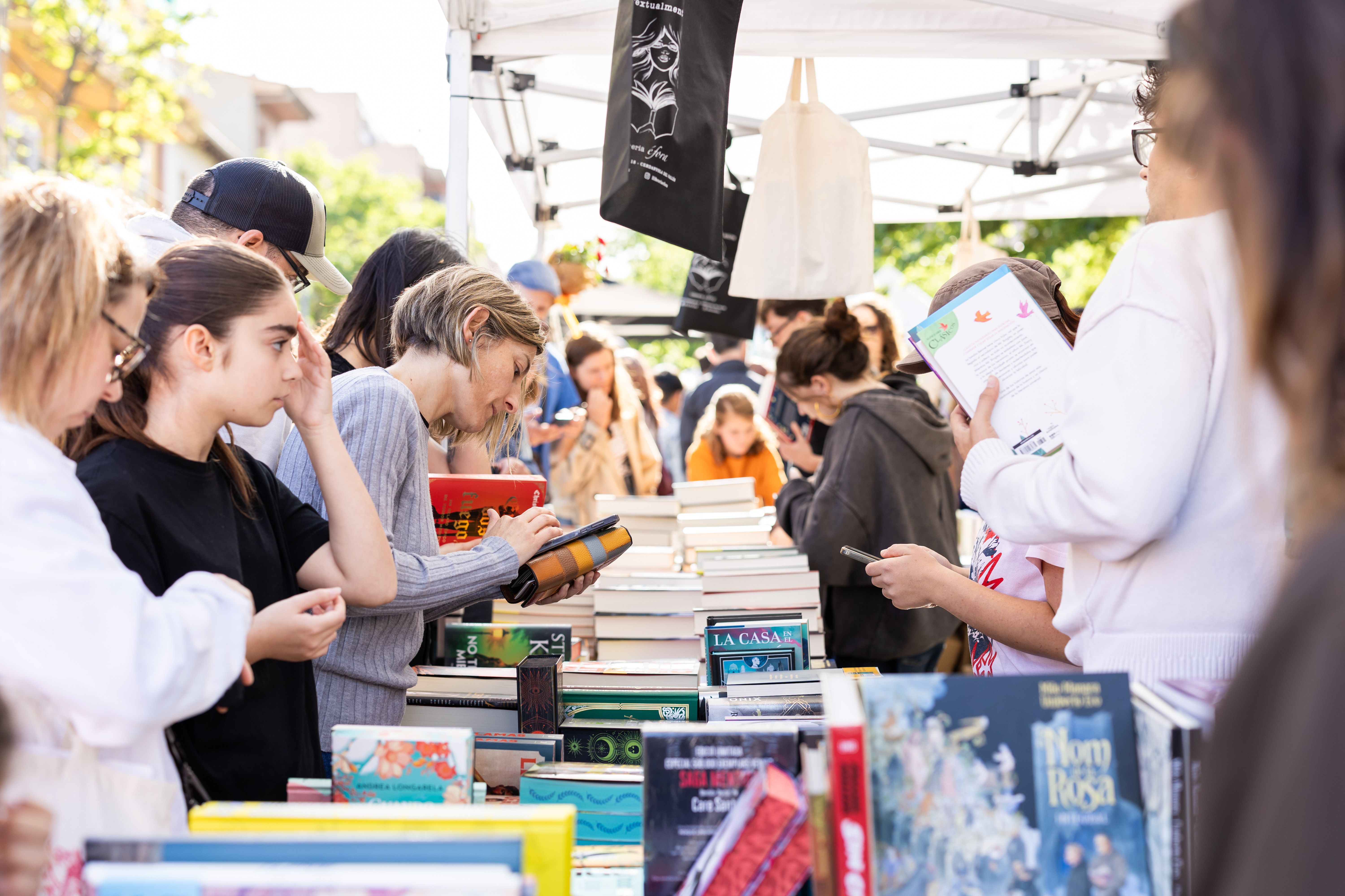 Parada de llibres per Sant Jordi a la plaça de l’Abat Oliba, amb lectors fullejant novetats durant la diada. FOTO Arnau Padilla
