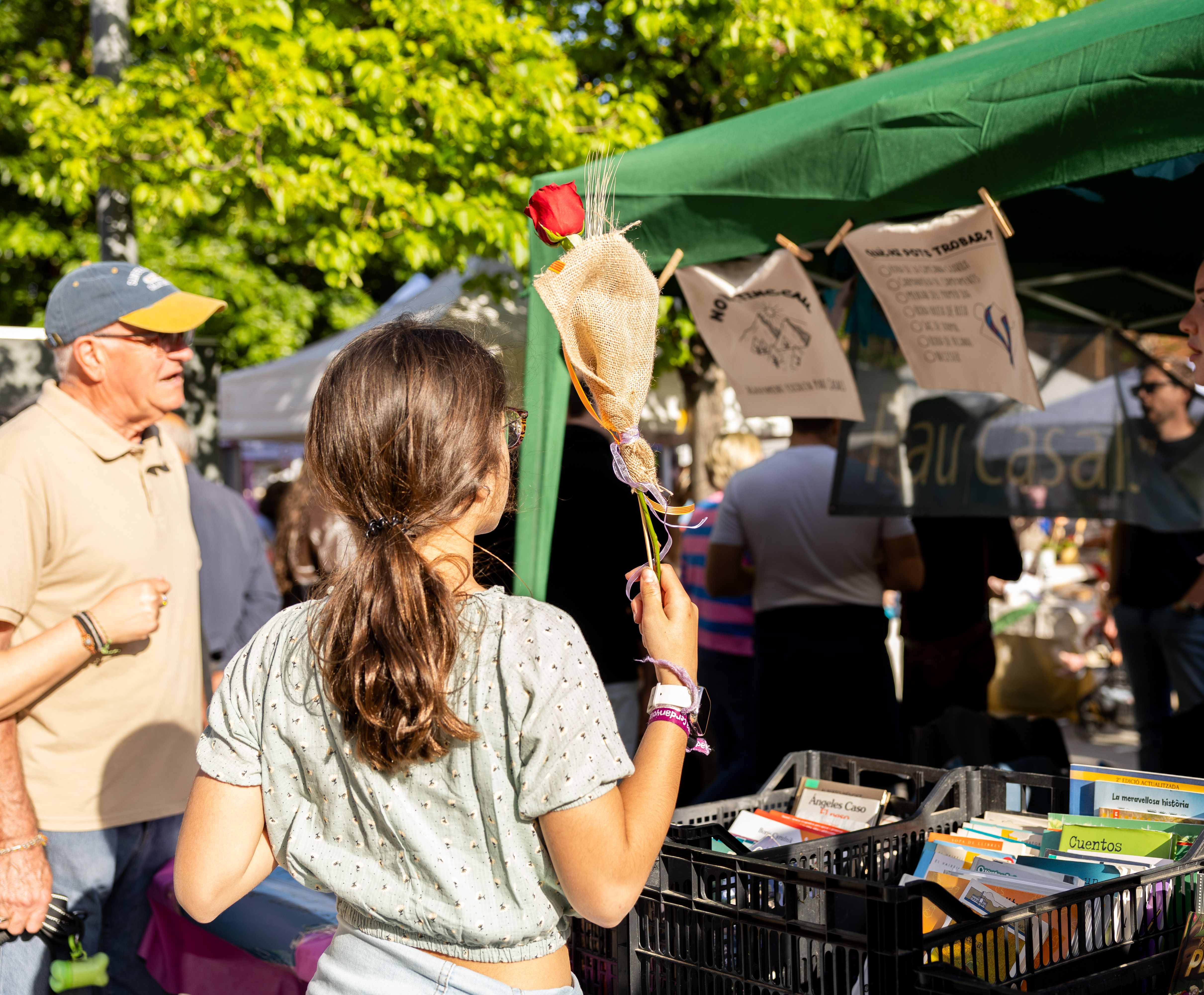 Una noia amb una rosa observa una parada de llibres de segona mà al mercat de Sant Jordi. FOTO Arnau Padilla