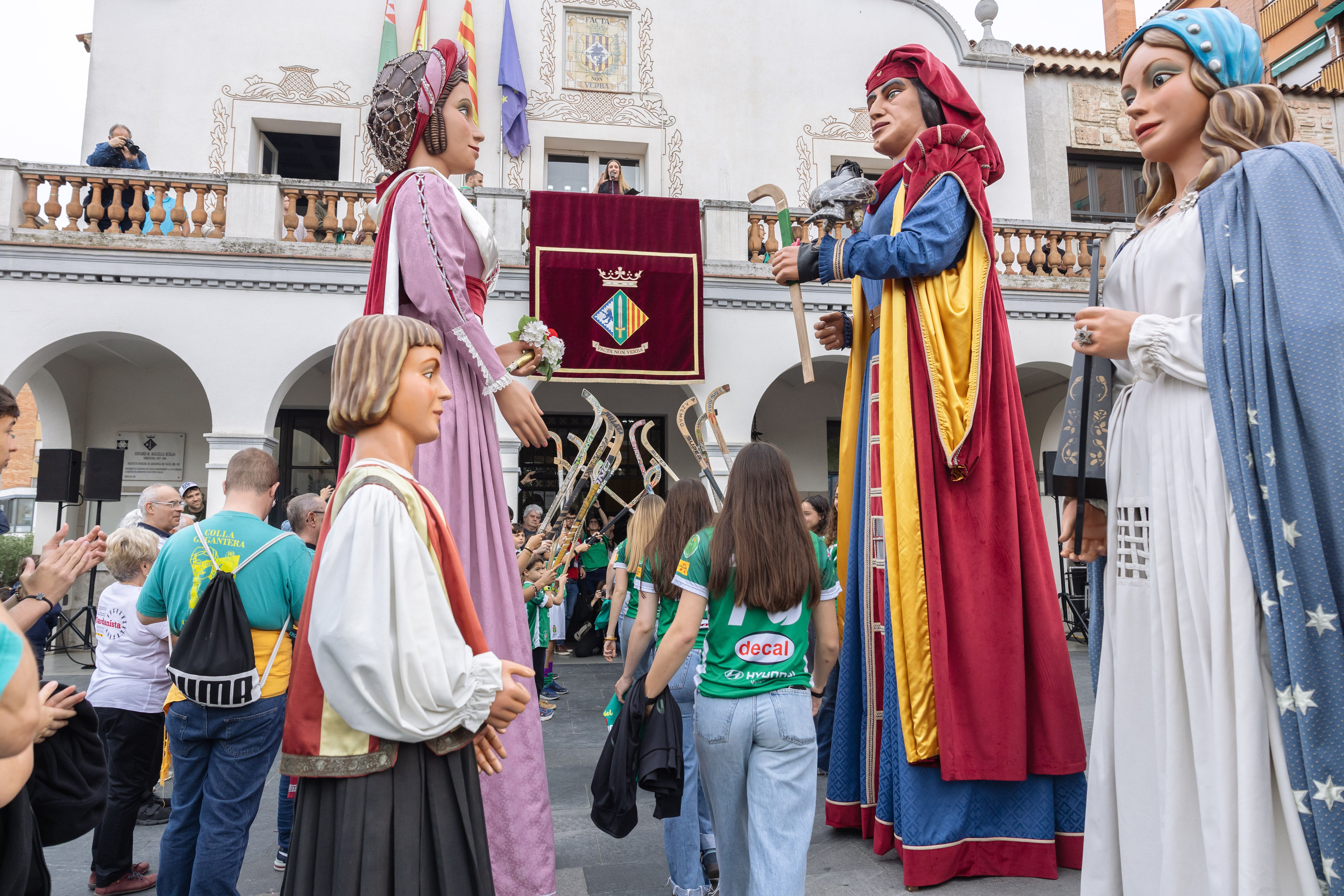 Els gegants obren el pregó davant de l’Ajuntament amb una plaça plena, mentre les jugadores d'hoquei creuen el passadis. FOTO: Arnau Padilla