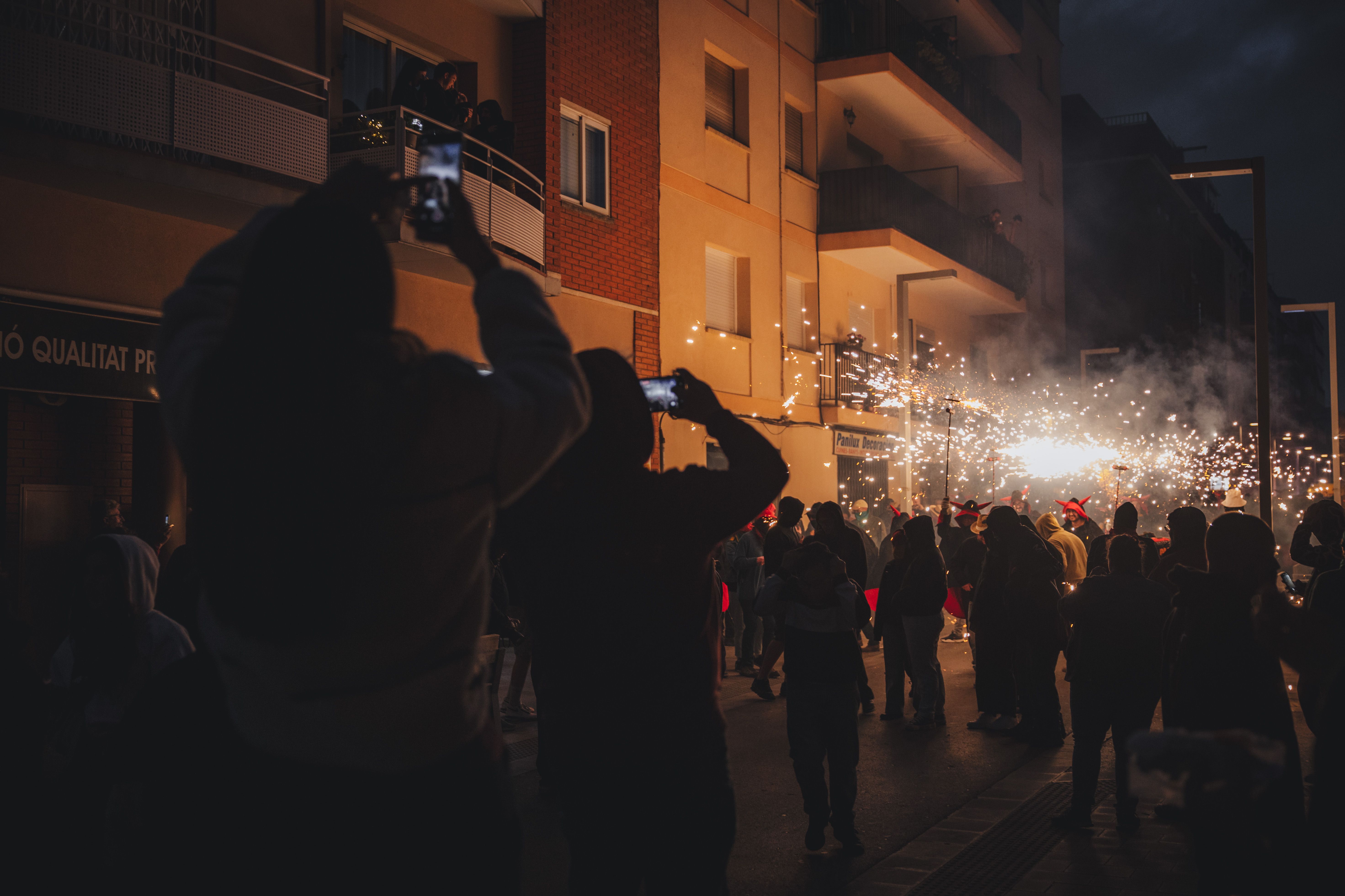 El públic segueix la cercavila de prop, capturant amb el mòbil l’espectacle de foc. FOTOS: Arnau Padilla