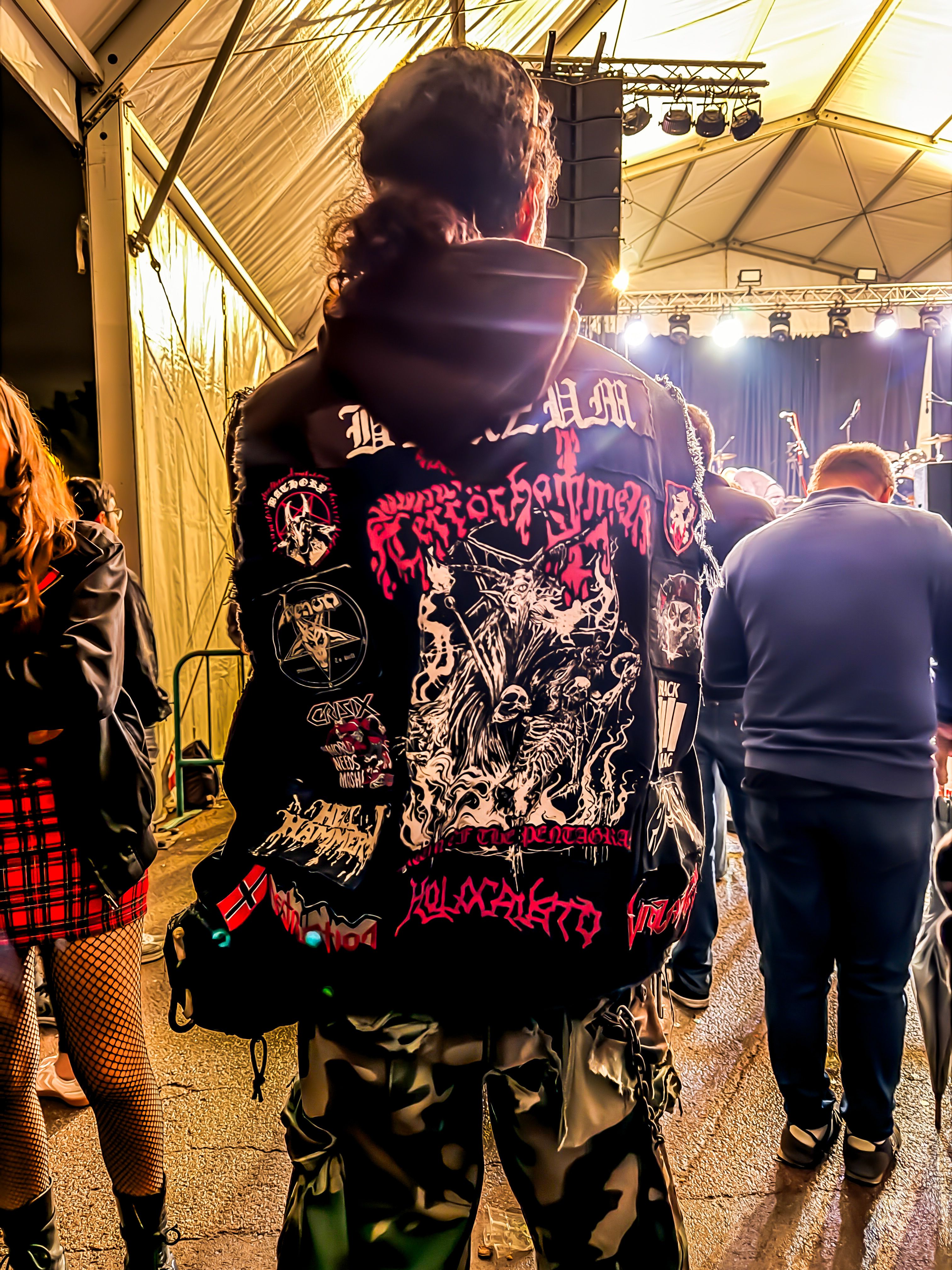 Un assistent amb una armilla plena de pedaços de bandes metaleres davant l’escenari. FOTO: Carme Monclús.