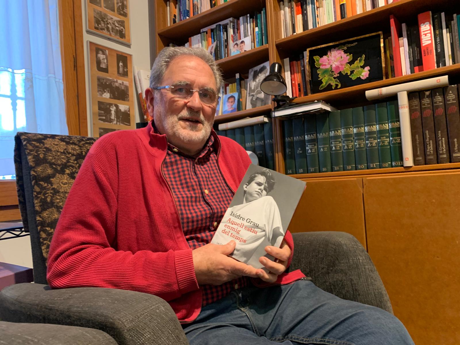 Isidre Grau, al despatx de casa seva a Cerdanyola, amb un exemplar de la seva nova novel·la 'Aquell estiu enmig del temps'. FOTO: Judit Josa