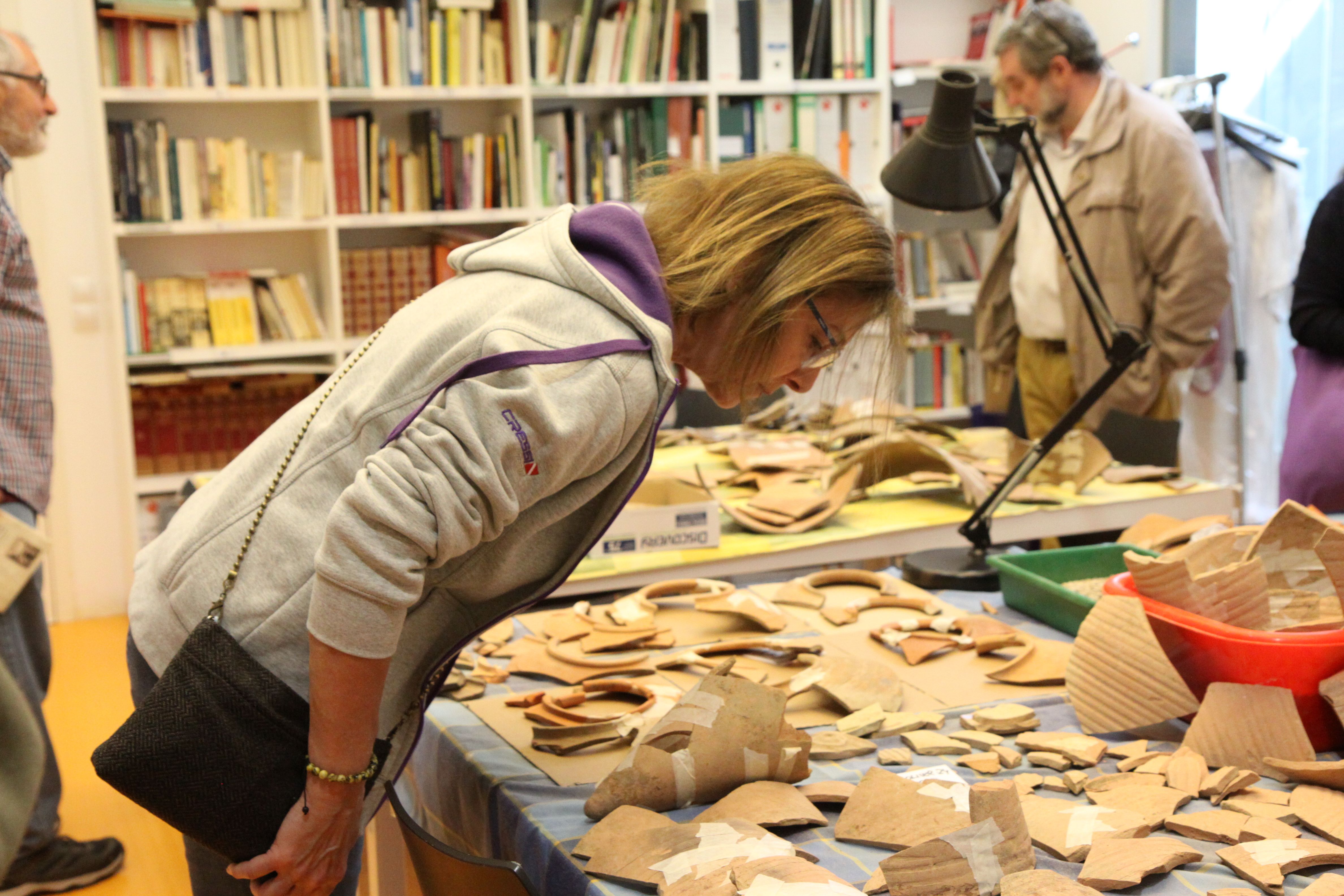 Usuaris del taller miren fragments de ceràmica a Ca n'Oliver. Foto: Laia Jubany