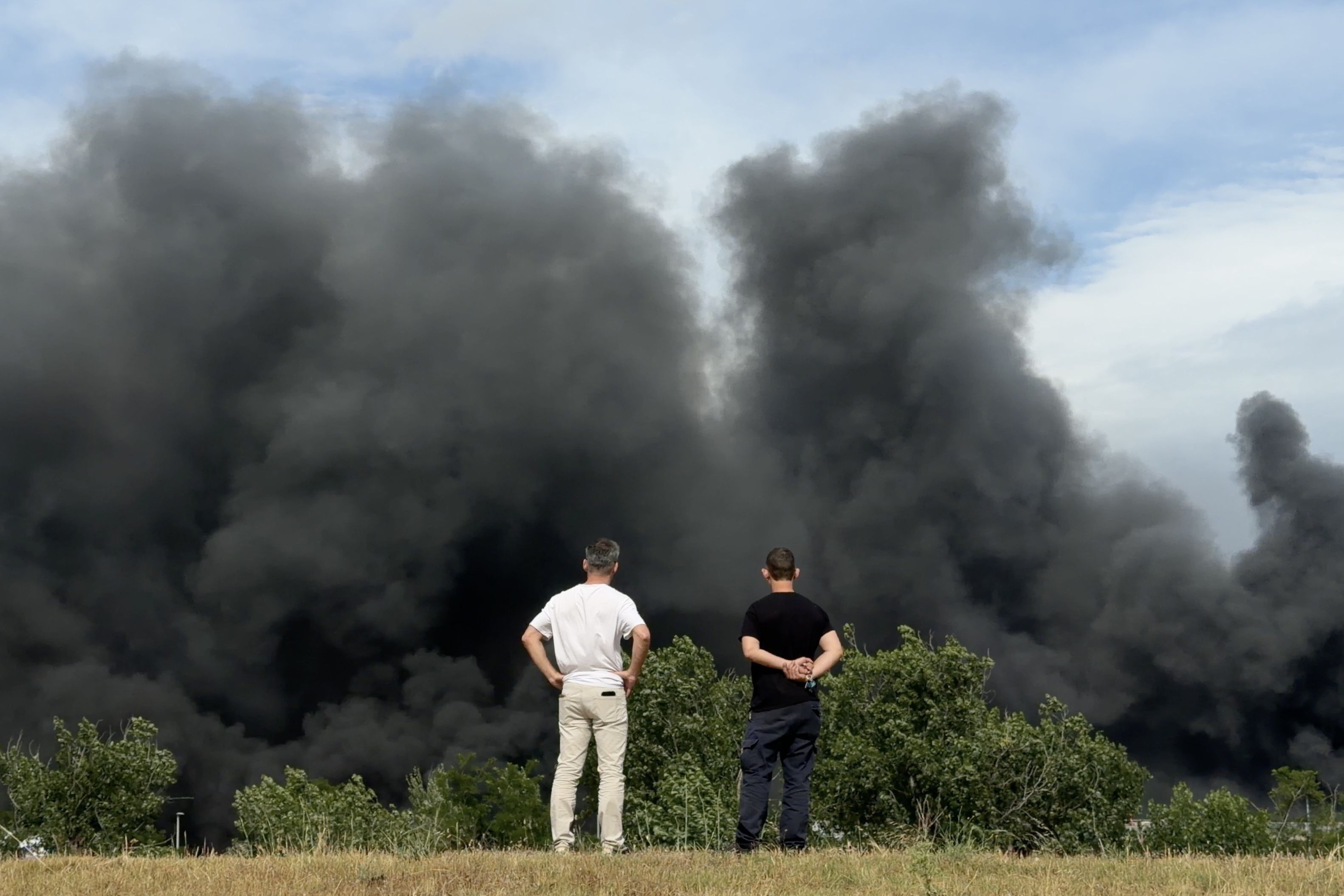 Dues persones miren un núvol de fum intens en el marc d'un incendi en una nau del polígon Torre del Rector de Santa Perpètua de Mogoda  FOTO: Albert Segura Lorrio