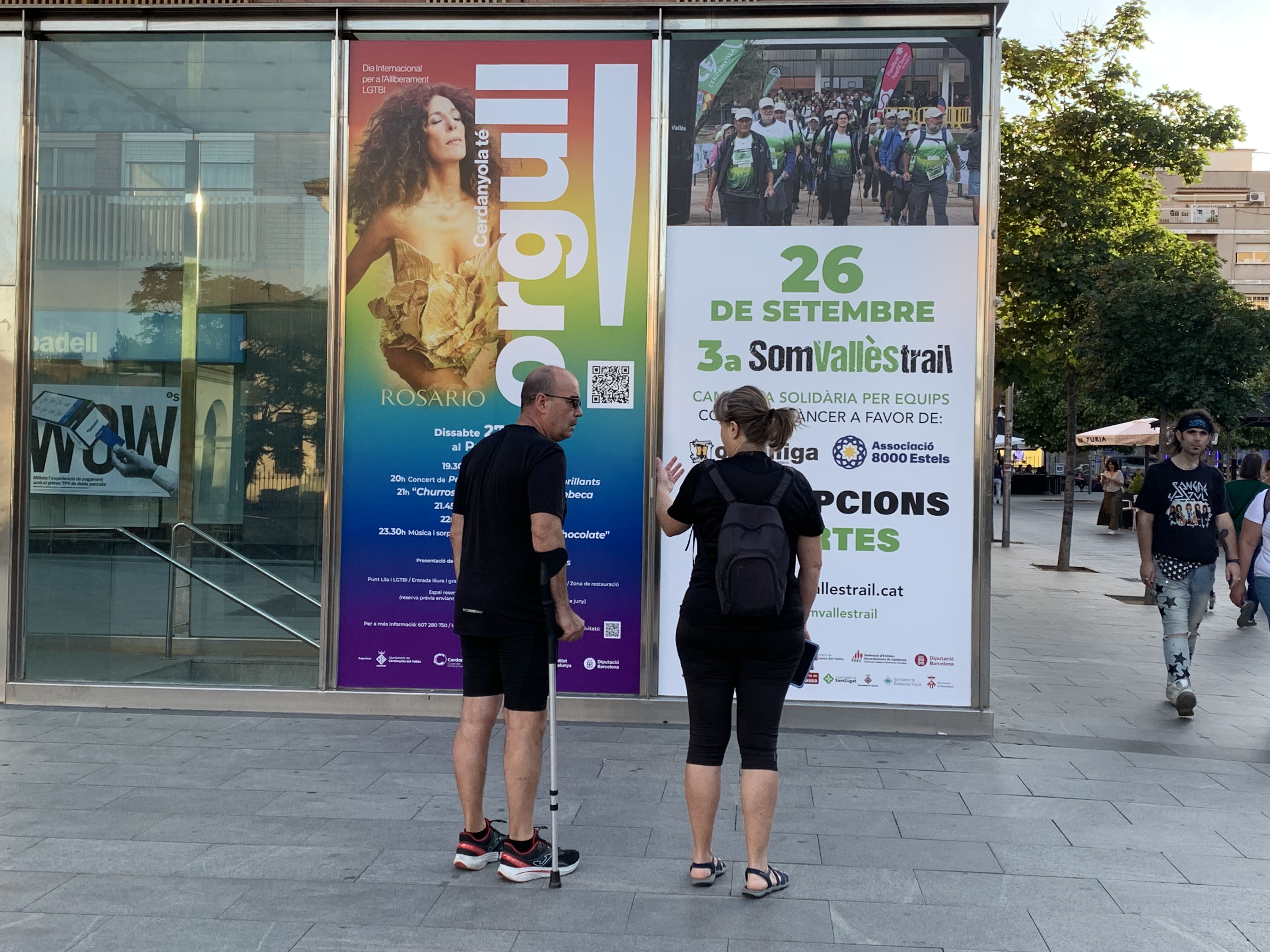 Dos vianants davant del cartell gegant que anuncia l'actuació de Rosario en la festa de l'Alliberament LGTBI, dijous a la Plaça d'Abat Oliba. FOTO: Judit Josa. 