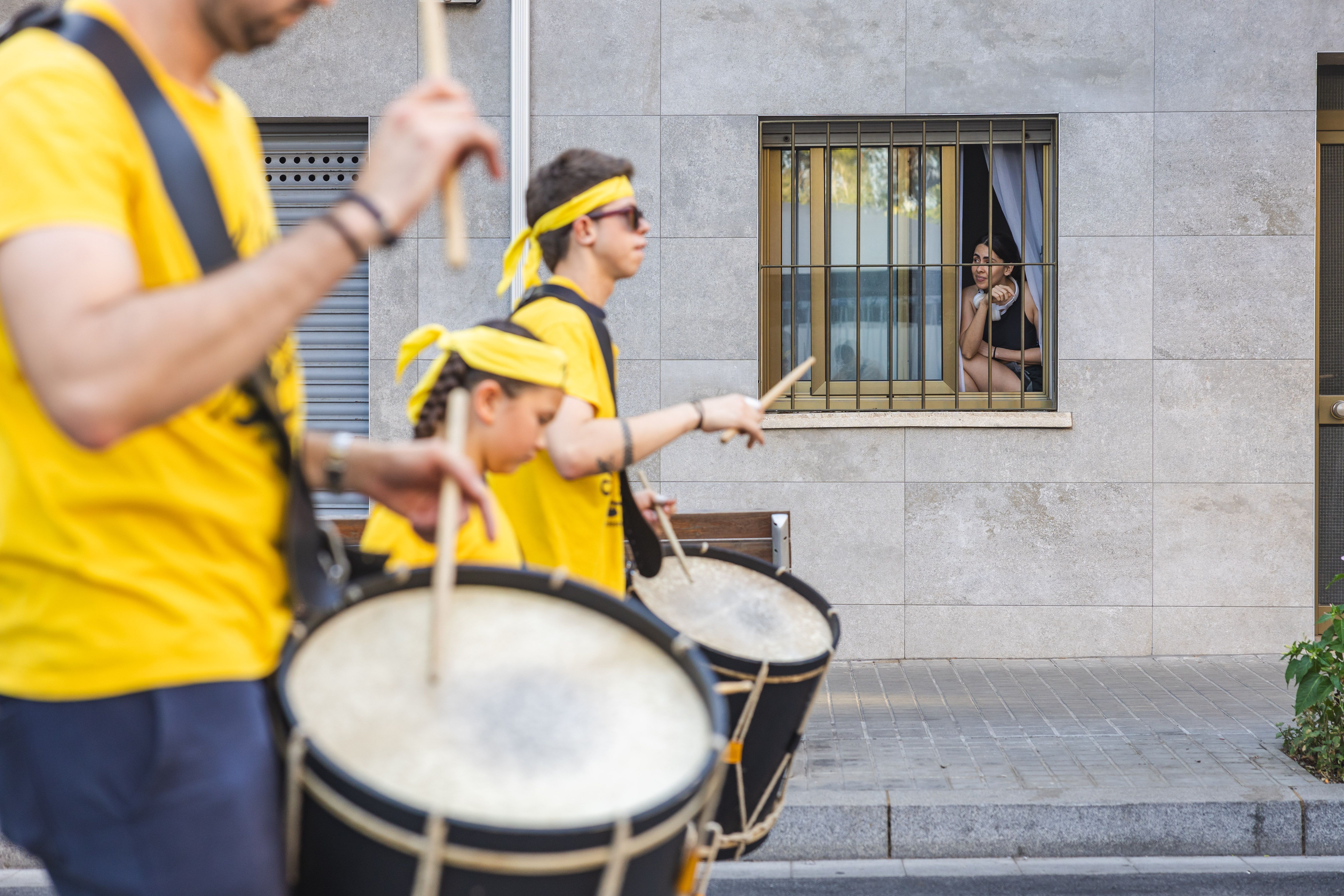El veïnat segueix des de les finestres el pas dels tabalers. FOTO: Arnau Padilla.