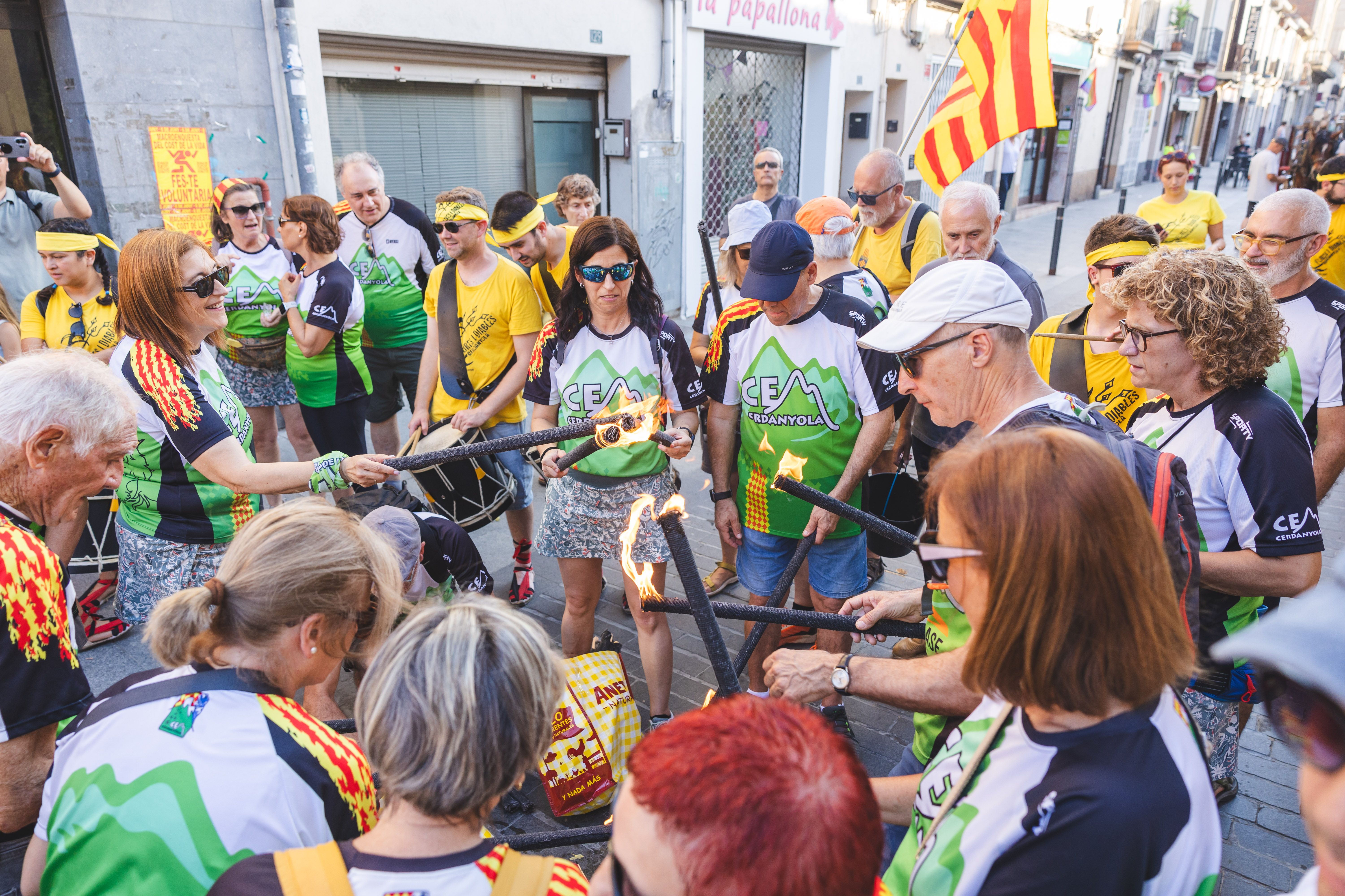 Els participants encenen les torxes amb la Flama del Canigó. FOTO: Arnau Padilla.