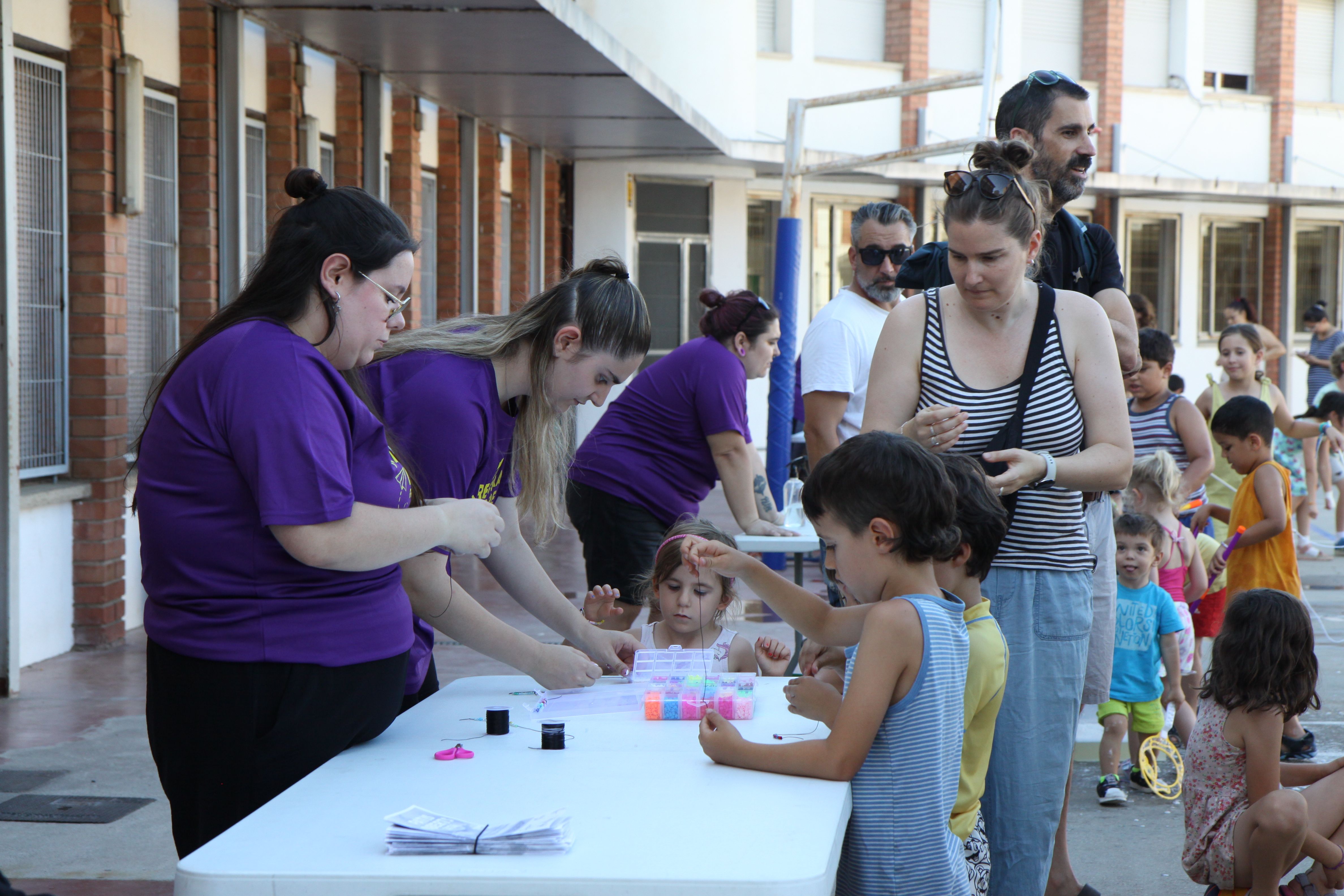 Un grup d'infants fent polseres per endur-se un record de la gran festa. Foto: Laia Jubany