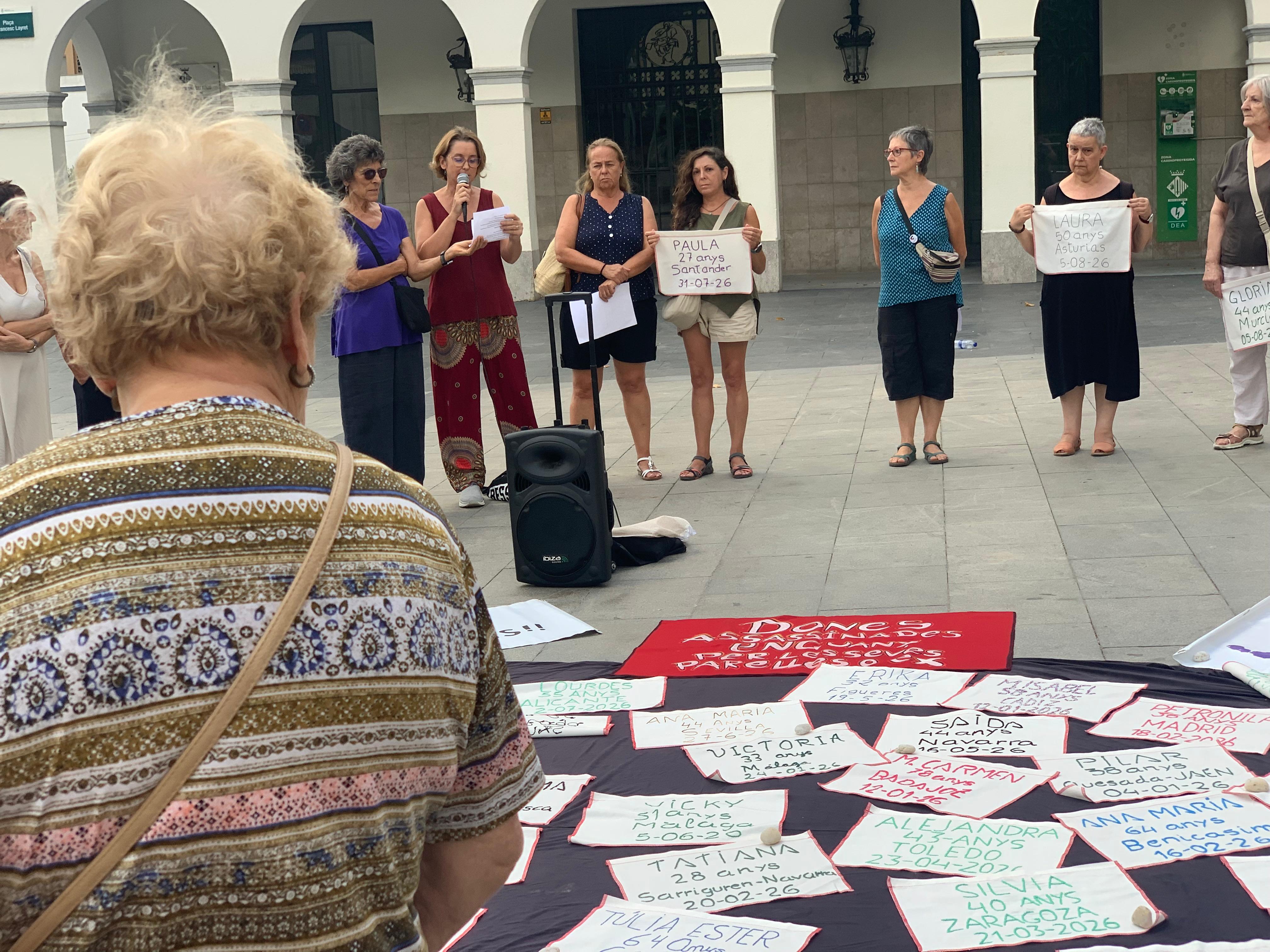 Una vianant s'atura mentre es llegeixen els noms de les víctimes de la violència masclista. FOTO: Judit Josa