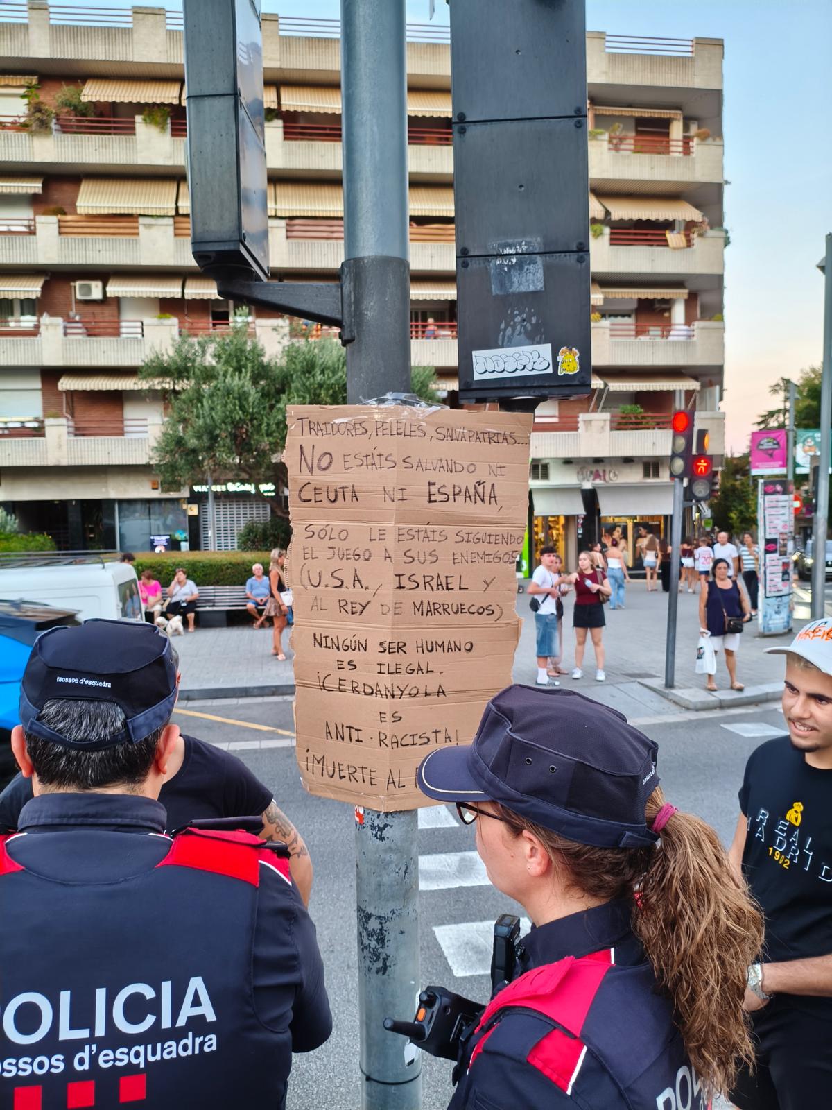 Els Mossos d'Esquadra intervenen després que un home pengi un cartell antiracista crític amb la concentració. FOTO: Cedida
