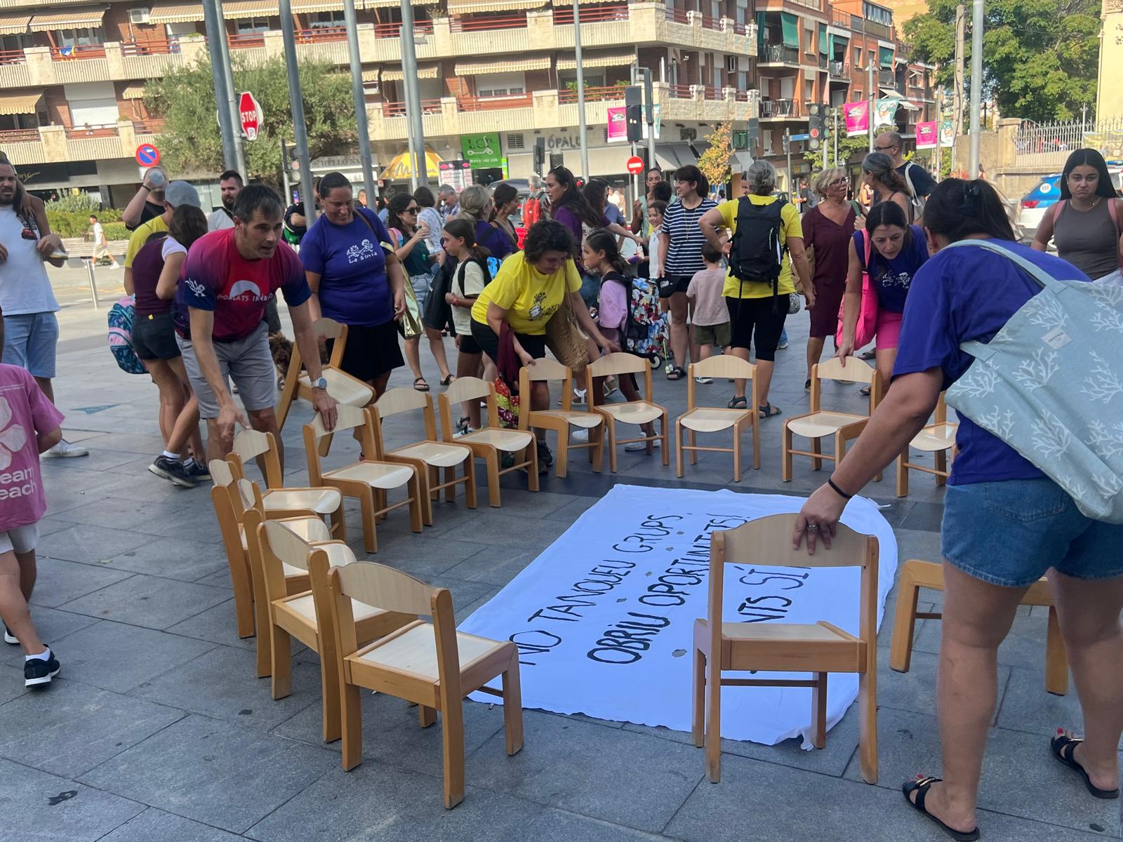 La comunitat educativa forma una rotllana amb 18 cadires davant de l’Ajuntament durant l’acció simbòlica. FOTO: Judit Josa