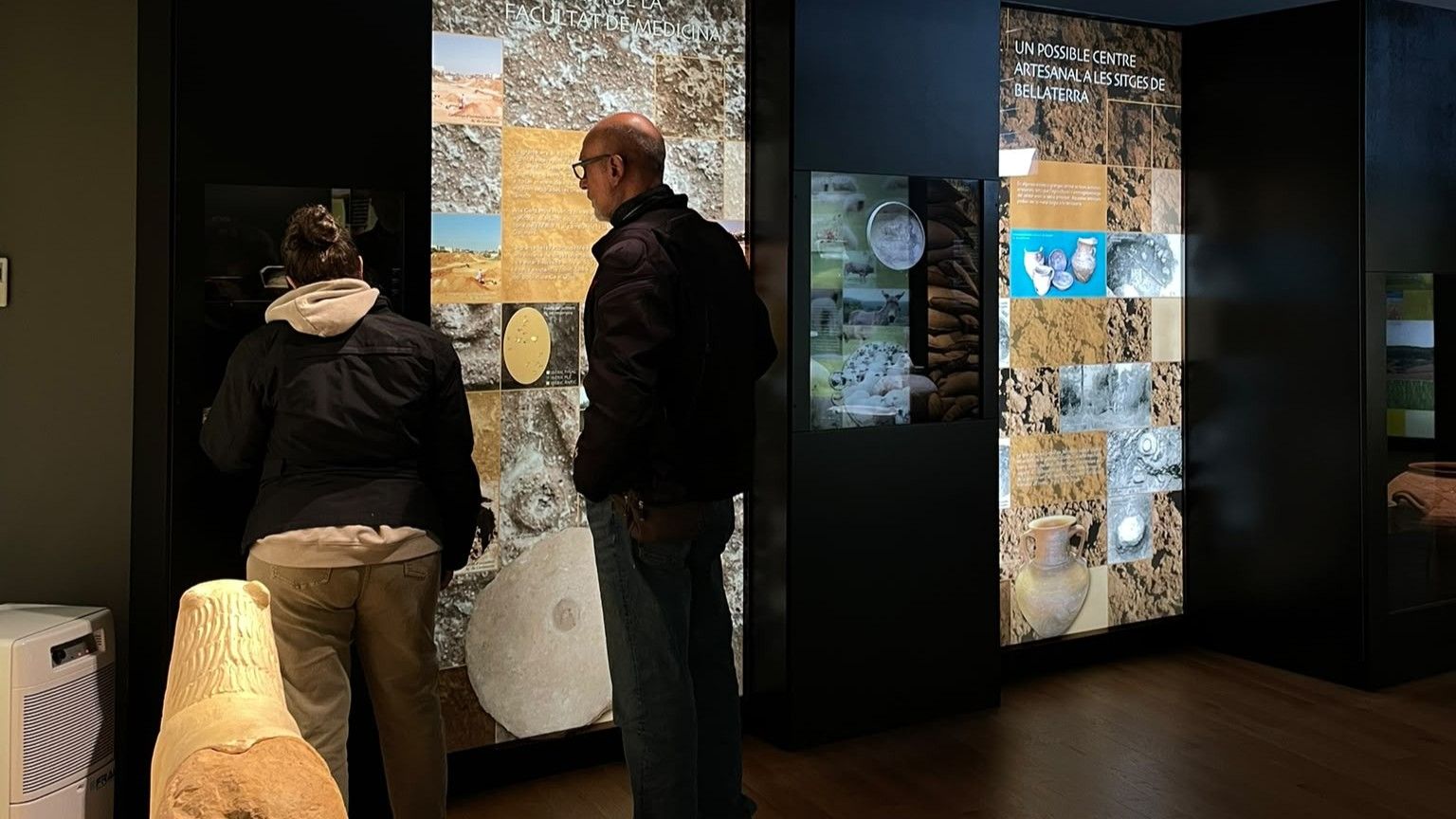 Un parell de persones es miren l'exposició permanent de Ca n'Oliver. Foto: Cedida