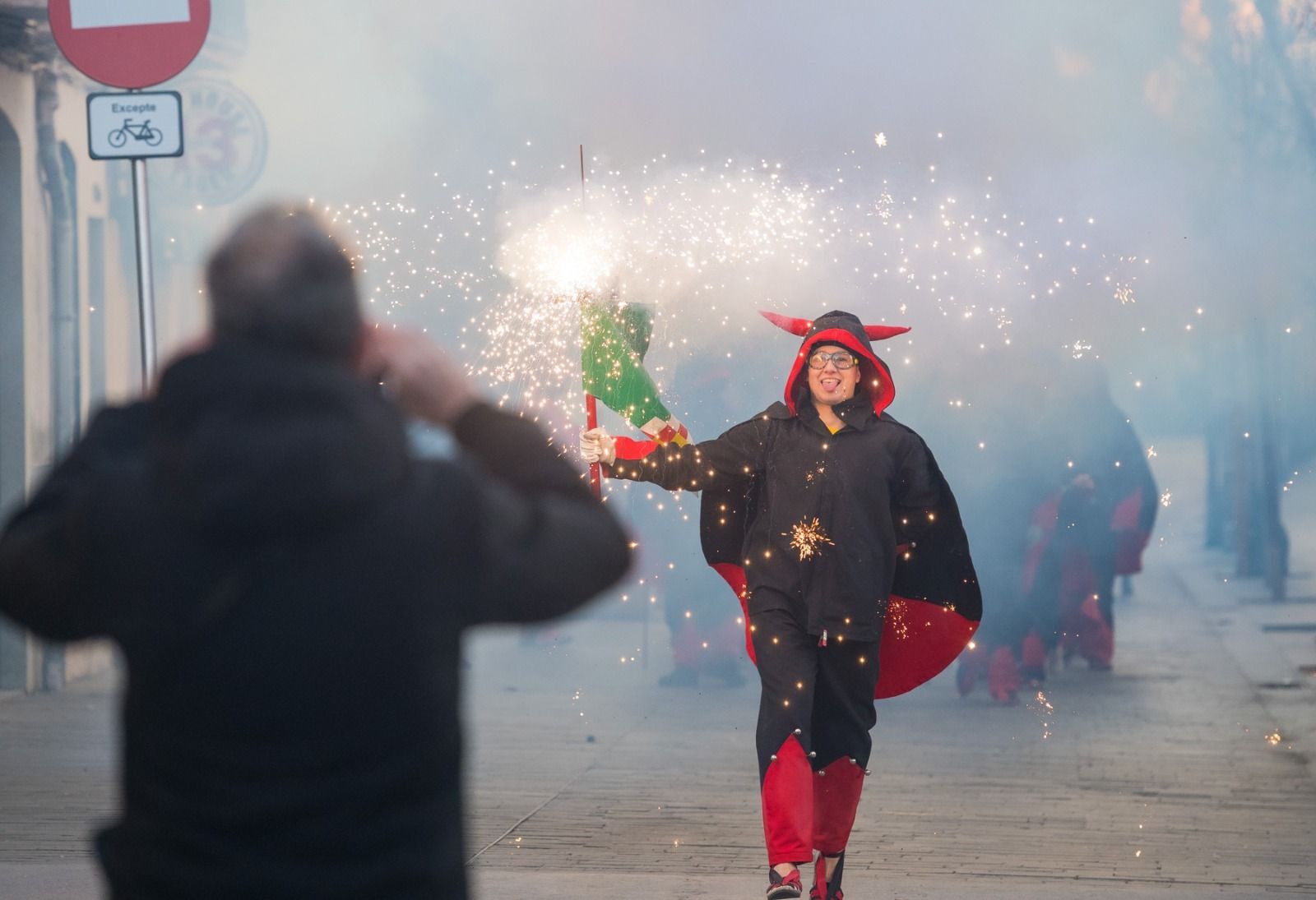 Albert Redondo Rodón, vestit com a diable, somrient, amb la massa encesa i una persona fotografiant-lo en primer terme. FOTO: Cedida