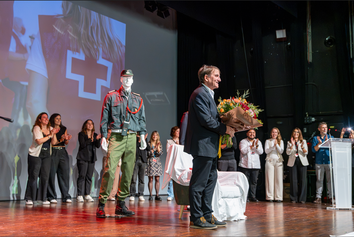 César Martínez rep un ram de flors entre els aplaudiments de l'equip de la Creu Roja, durant l'homenatge per la seva jubilació. FOTO: Creu Roja